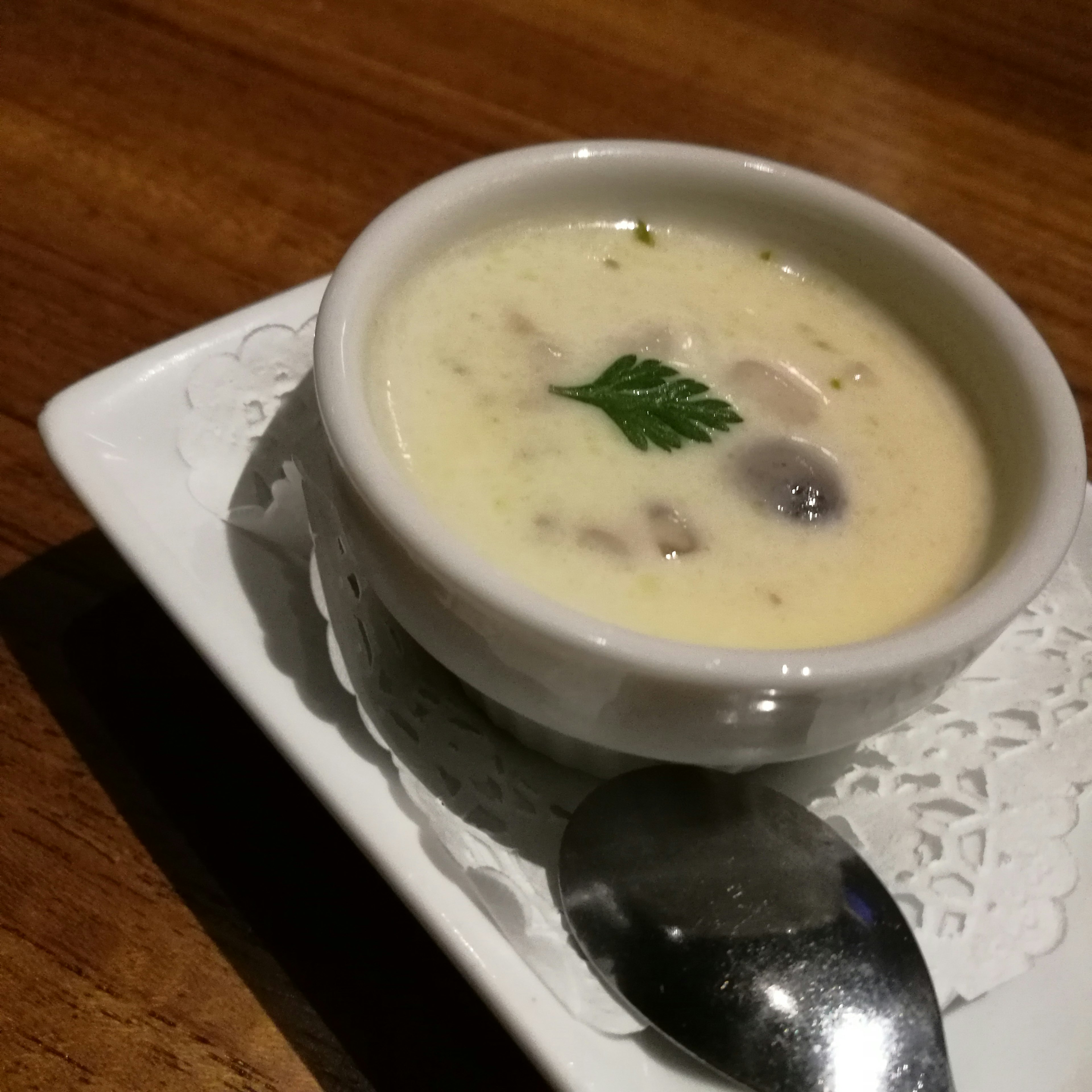 Soupe crémeuse servie dans un bol blanc garnie d'une herbe verte