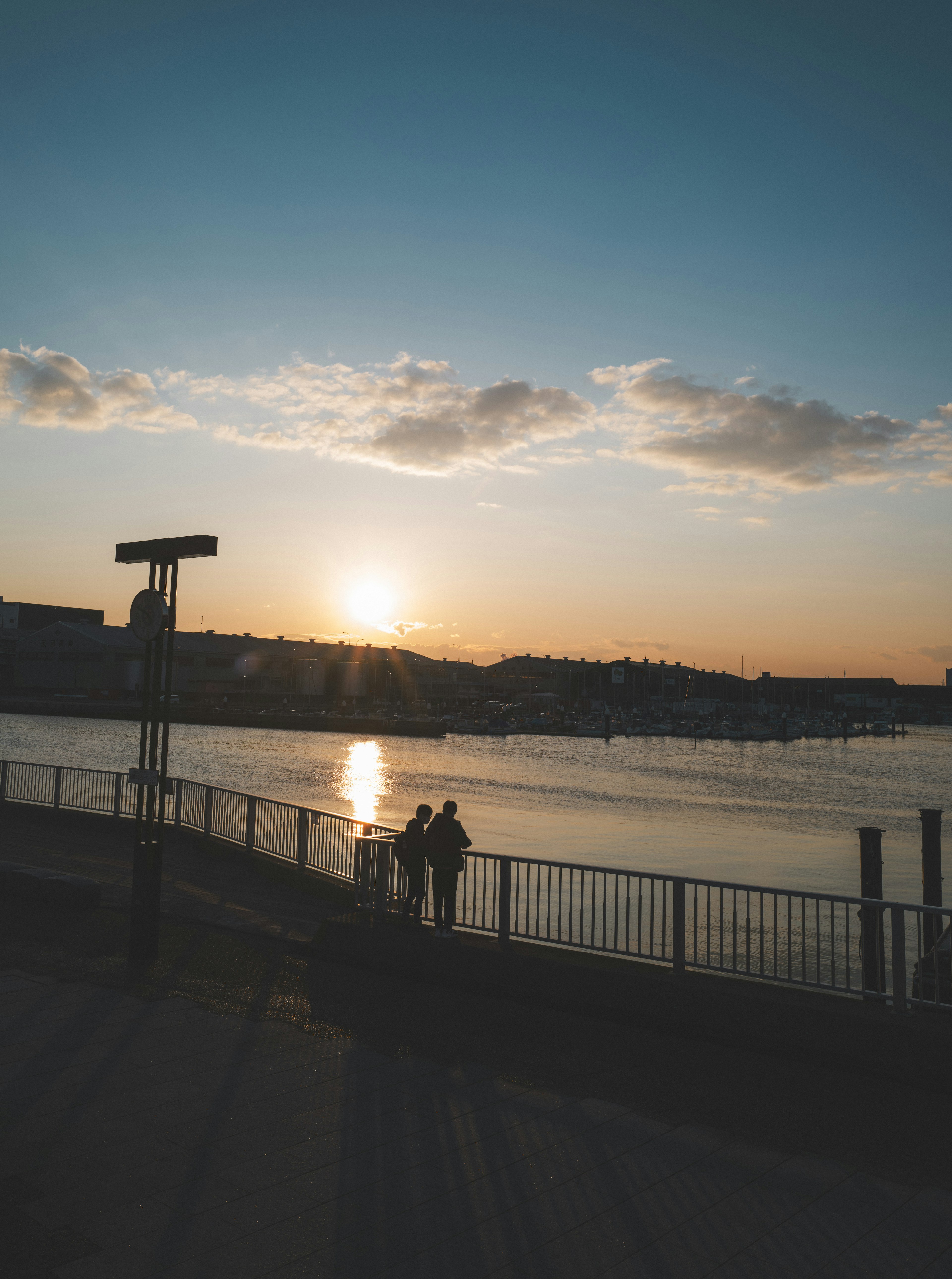 Silhouette eines Paares, das den Fluss mit einem Sonnenuntergang im Hintergrund betrachtet