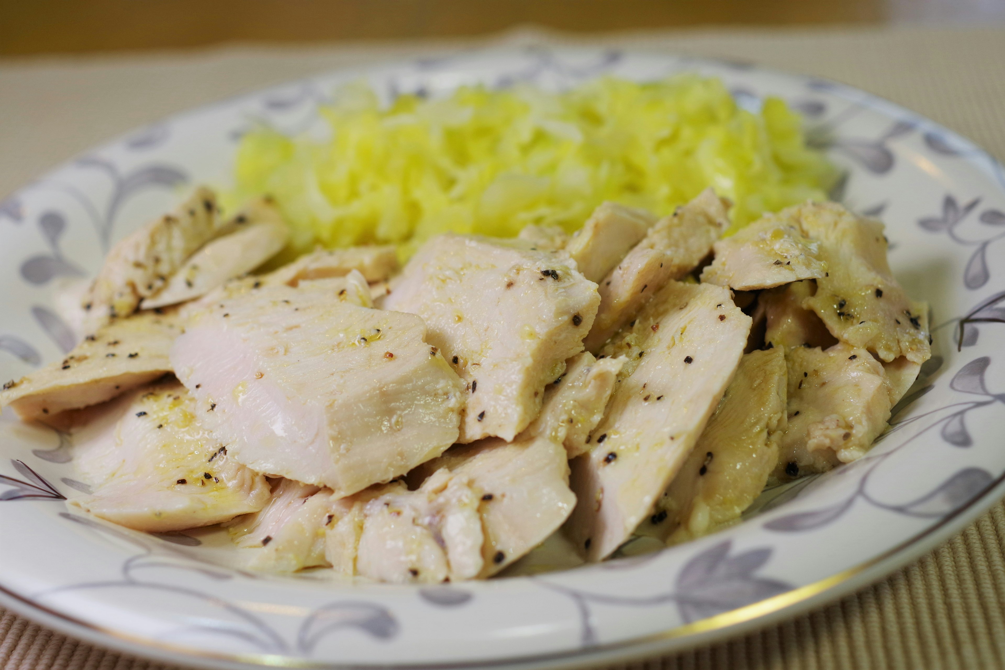 Sliced chicken served on a white plate with yellow rice