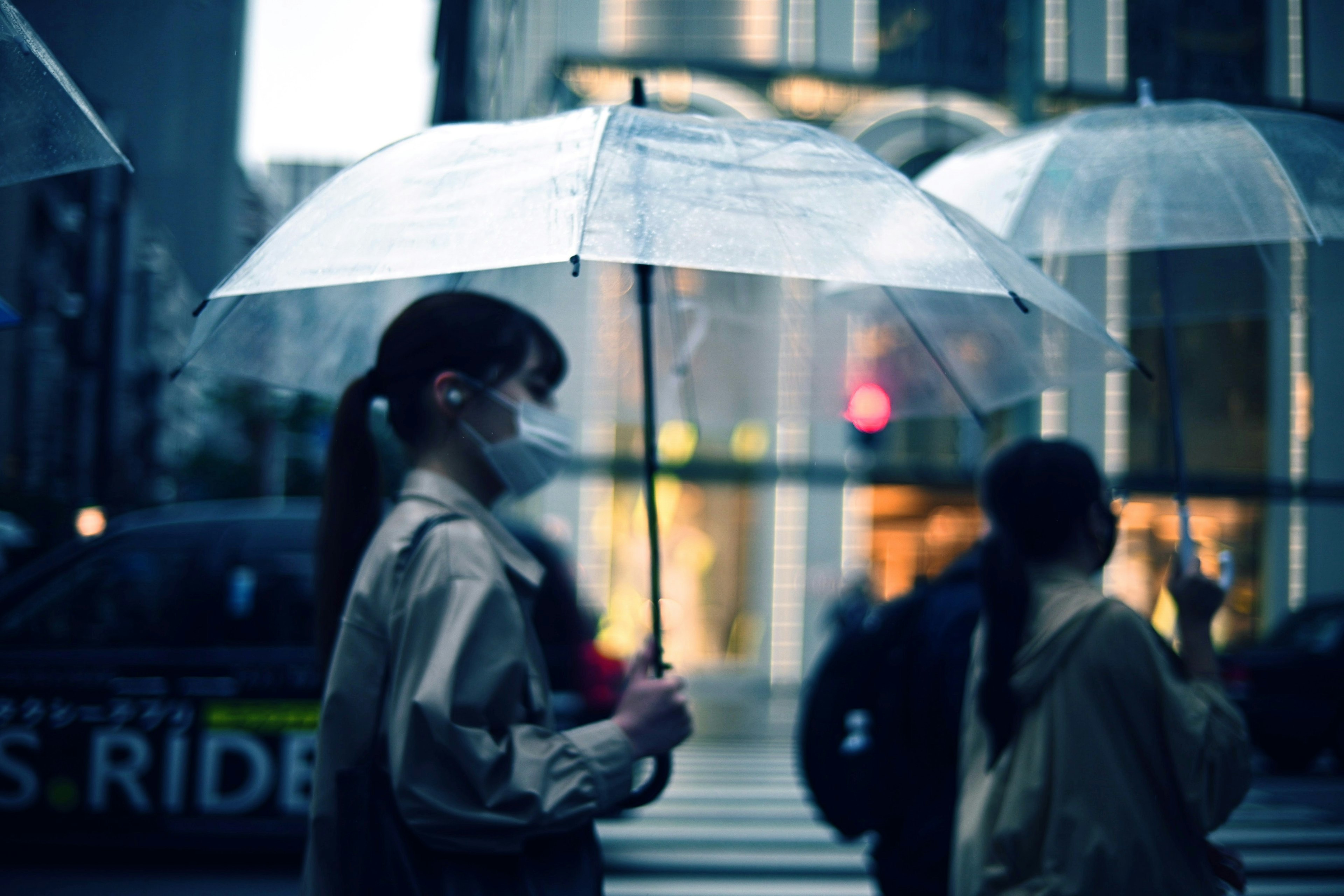 雨の中で透明な傘を持つ女性が街を歩いているシーン