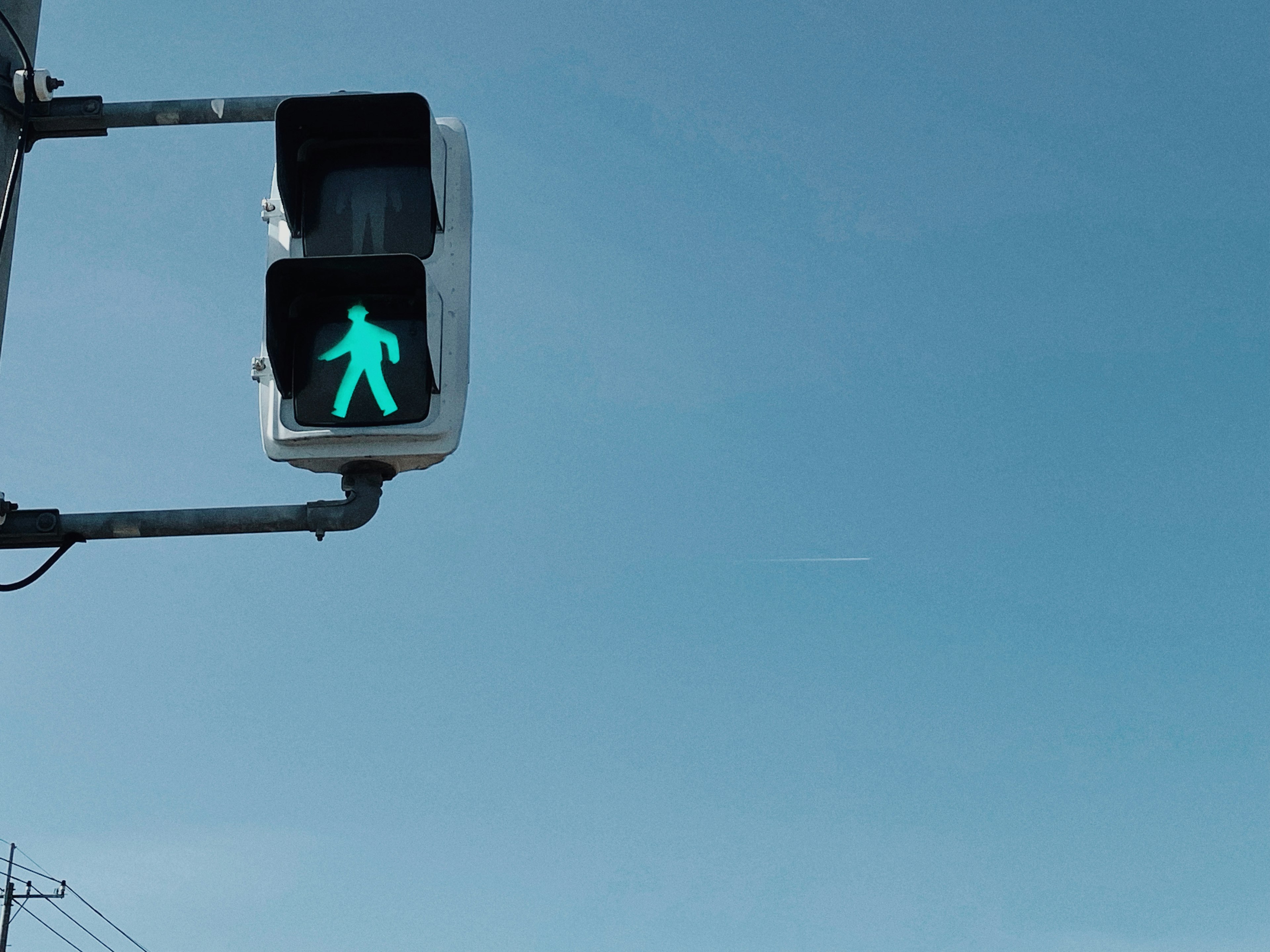 Segnale pedonale verde contro un cielo blu