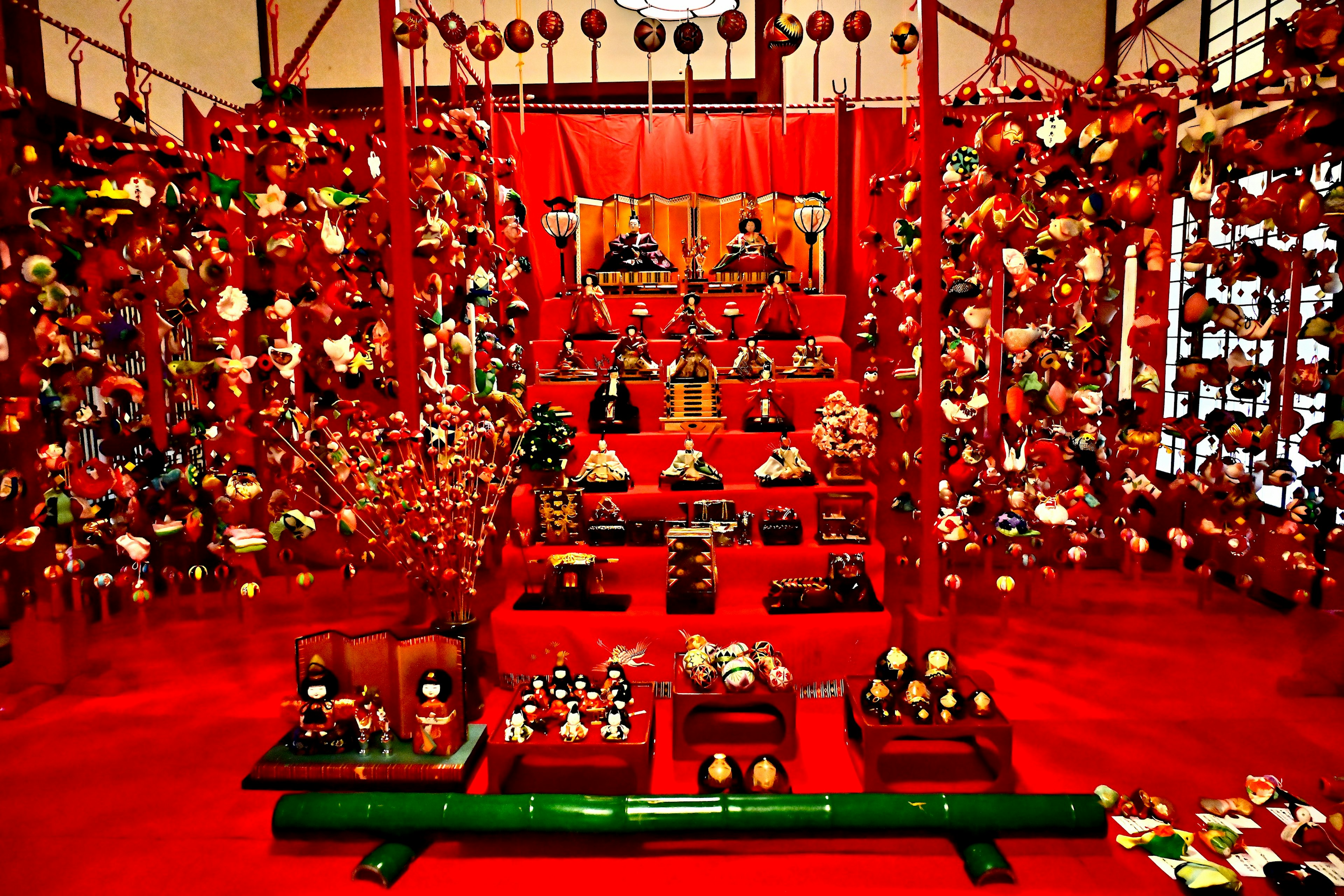 Exposition vibrante de poupées hina japonaises traditionnelles et de décorations suspendues sur fond rouge