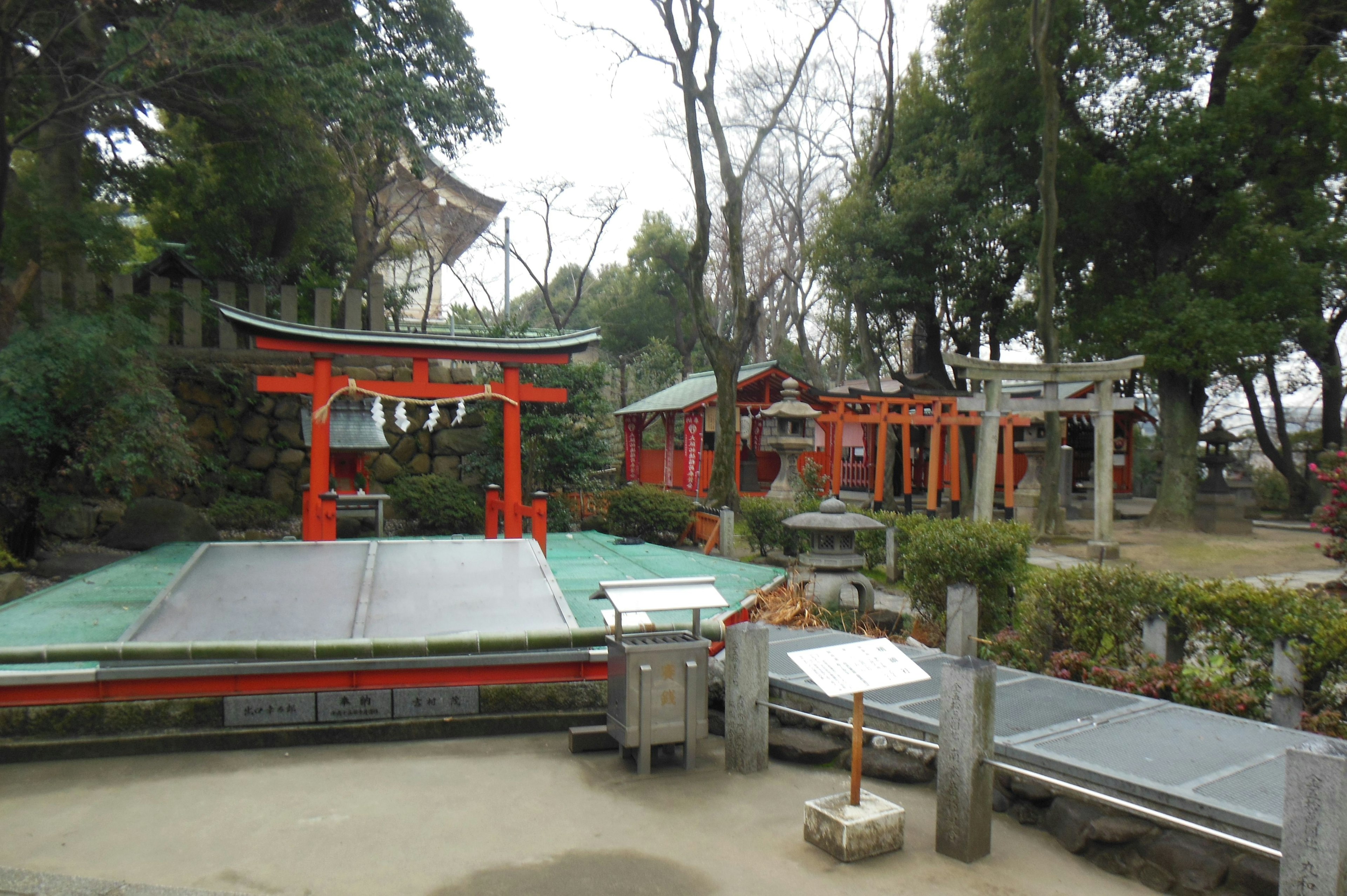 风景如画的神社景观，红色鸟居环绕着绿色植物