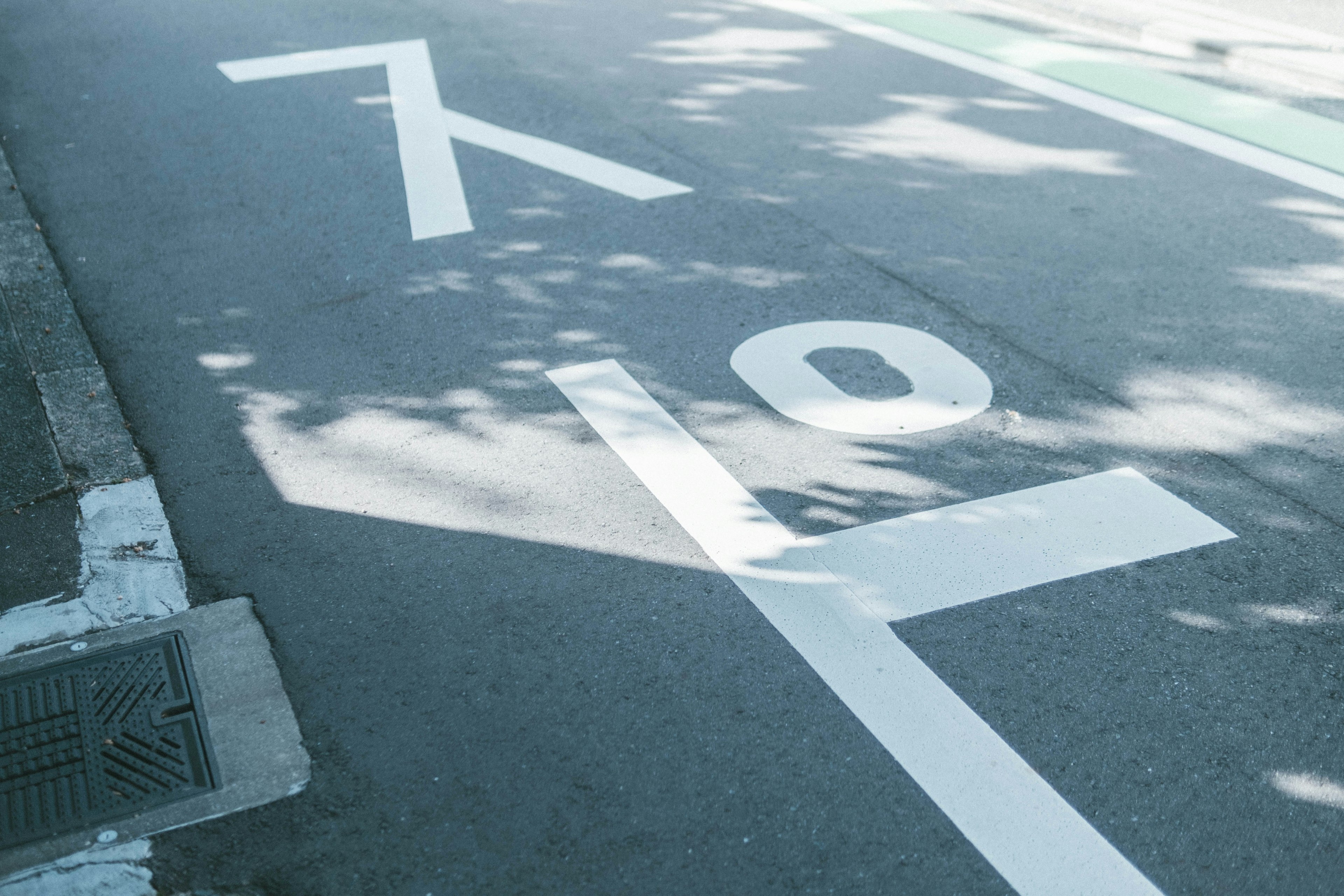 道路に描かれた白い文字と影のある風景