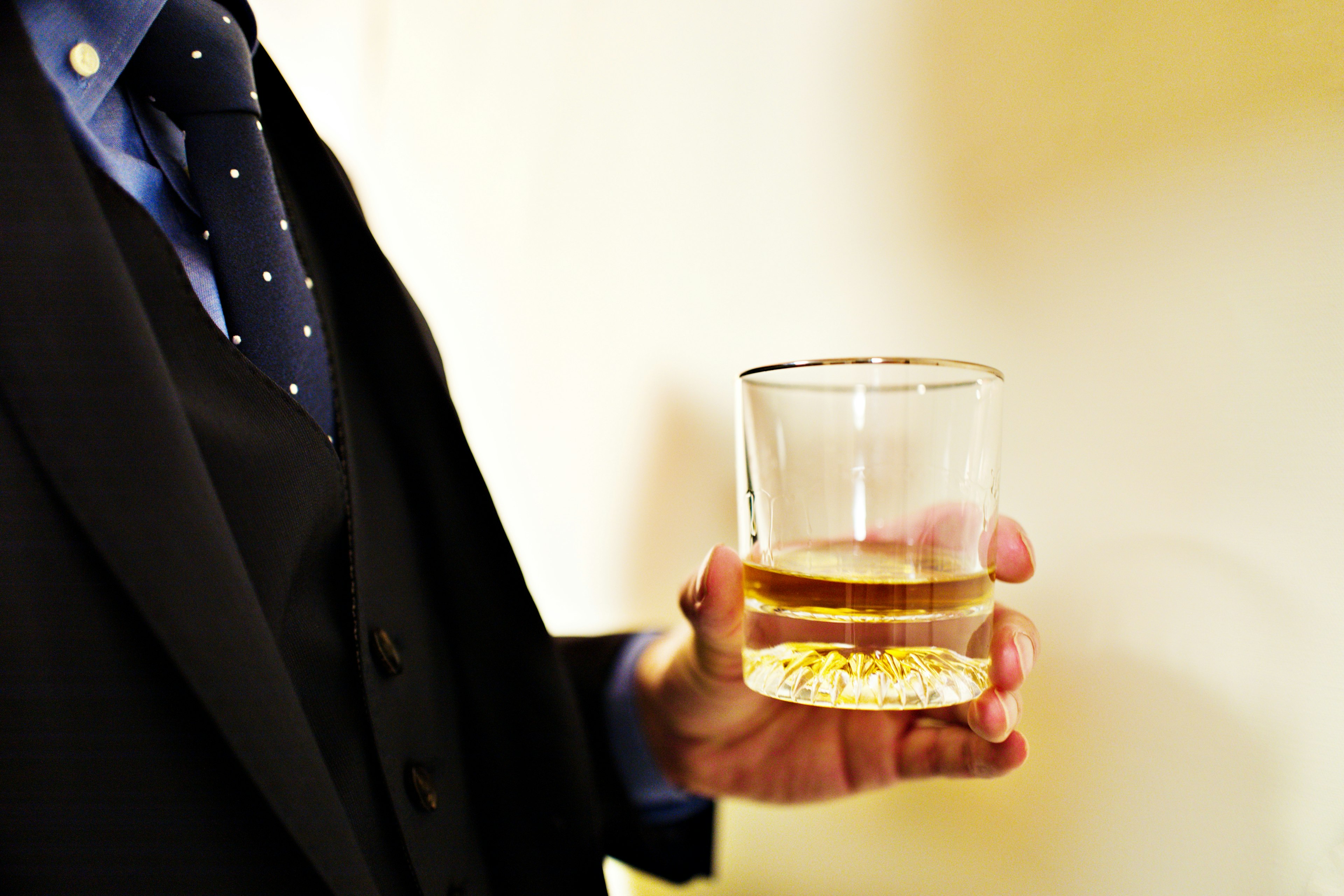 Un homme en costume tenant un verre de whisky