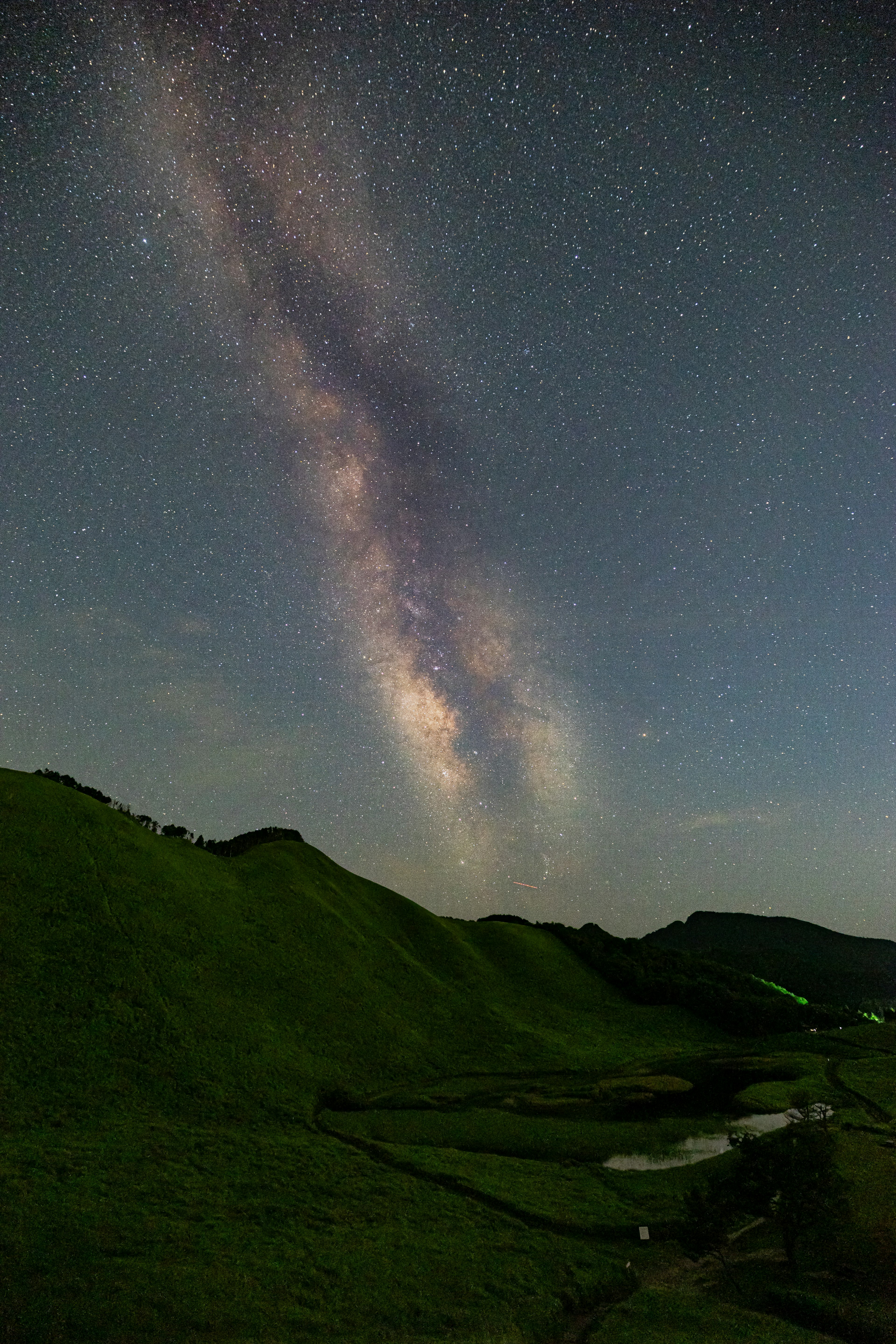 星空下綠色丘陵與銀河的美麗景色