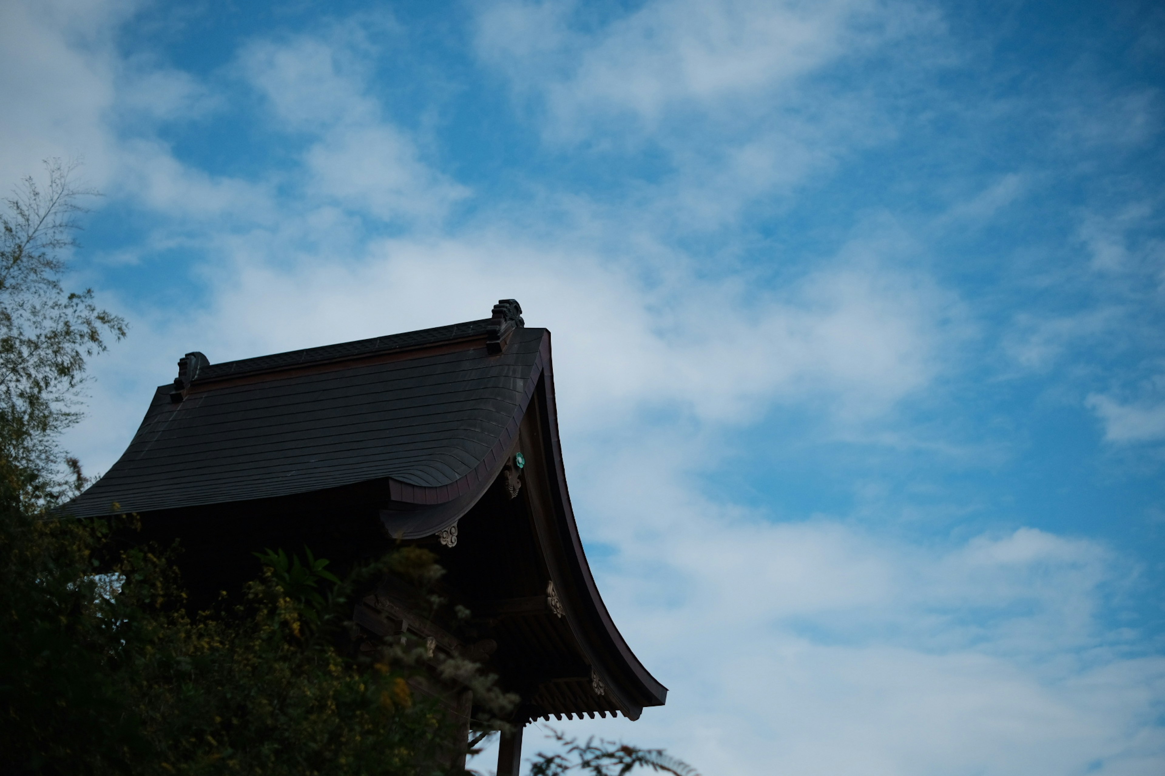 青空と雲の下にある伝統的な日本の建物の屋根