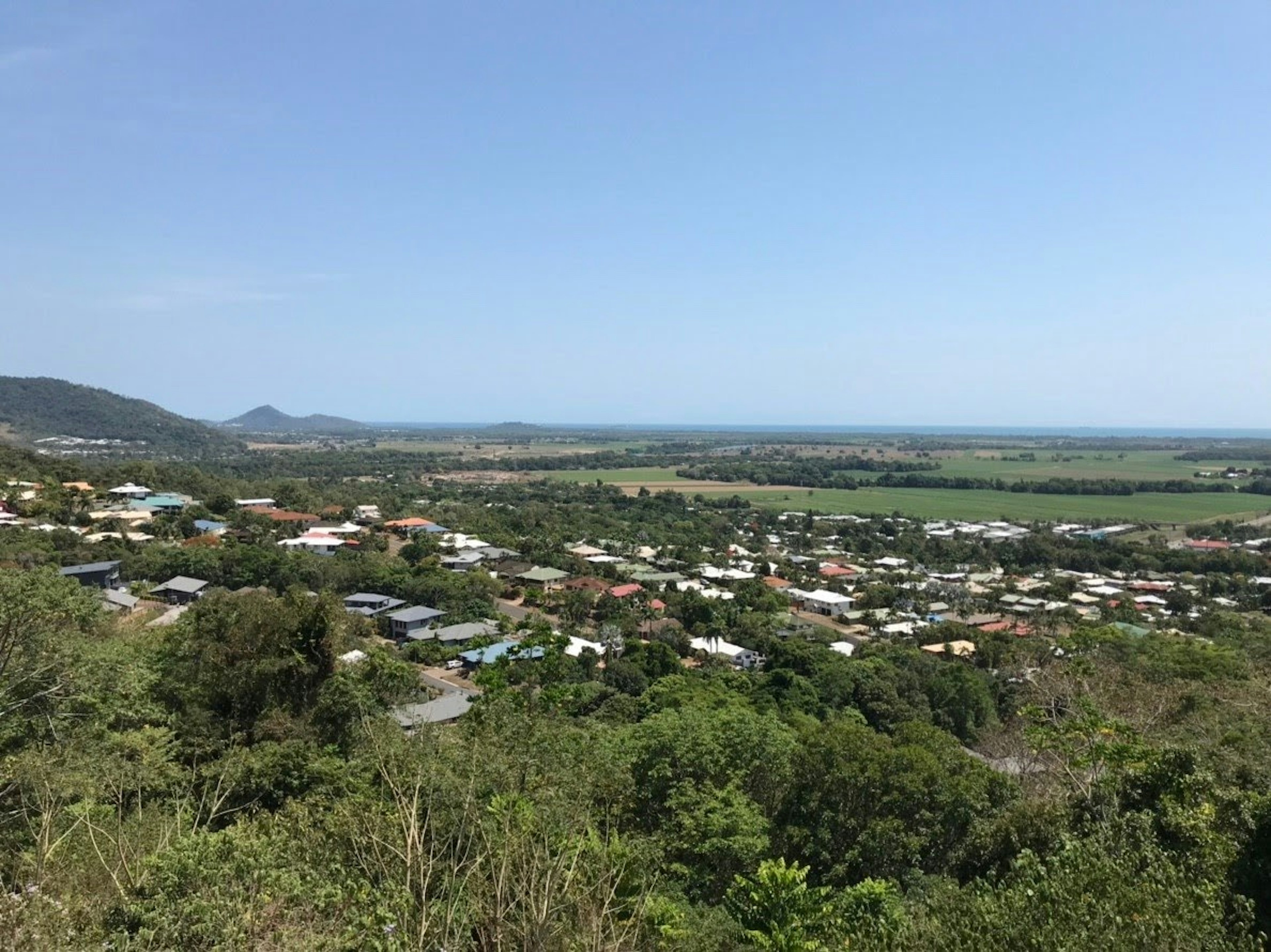 Panoramic view of a green landscape with houses and the sea in the distance