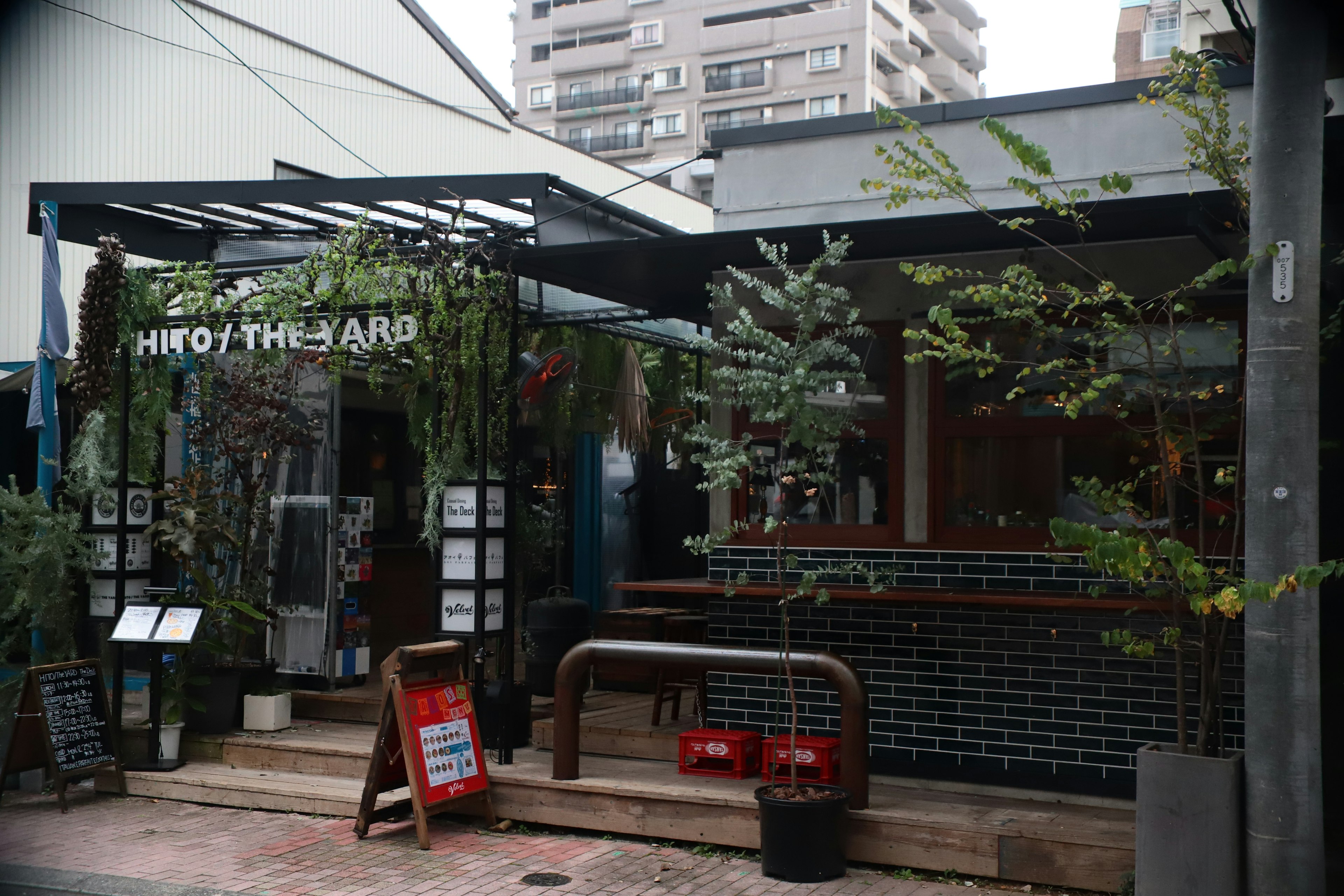 Extérieur d'un café moderne avec des décorations de verdure et un bar en carrelage noir