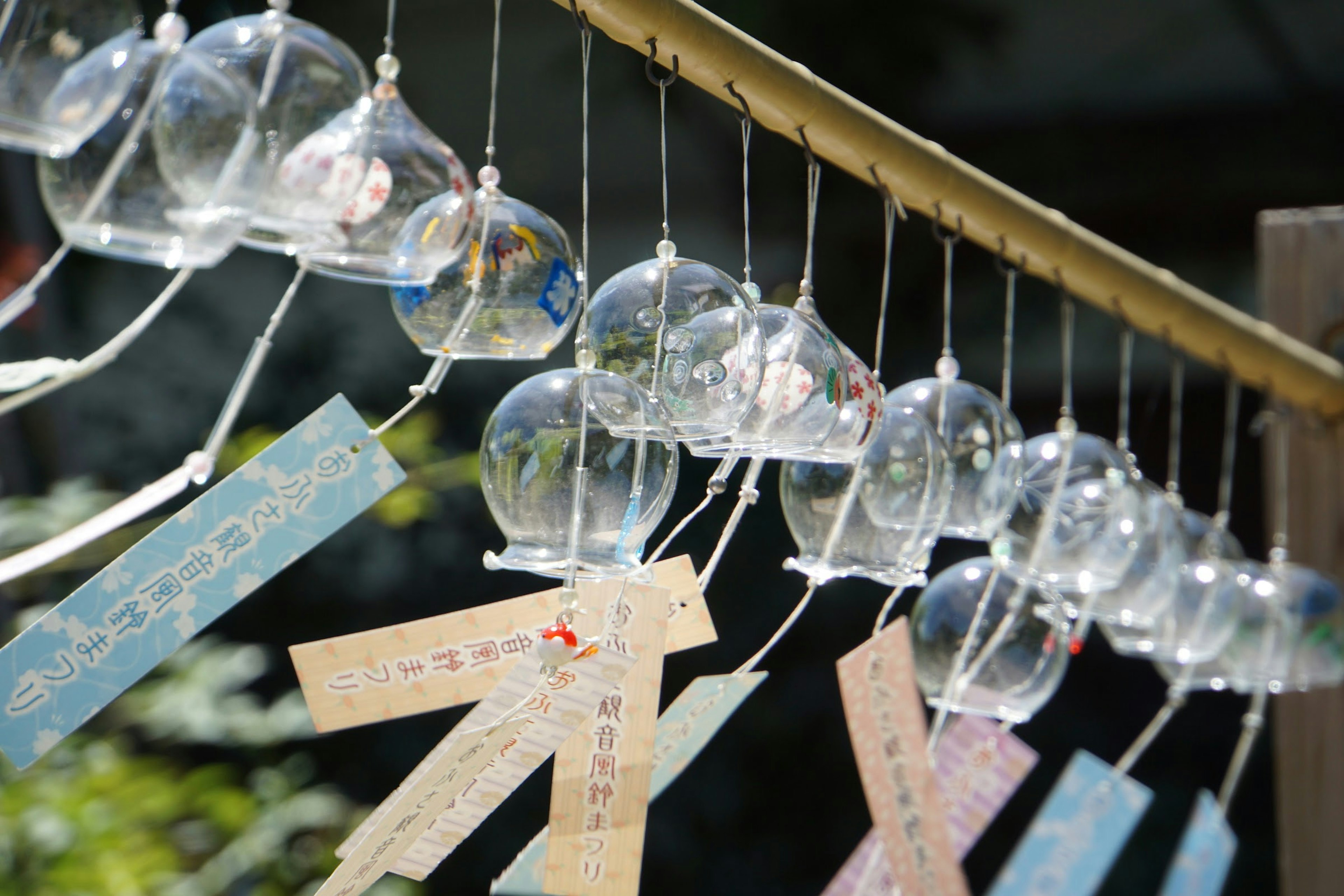 Photograph of wind chimes hanging with colorful strips beneath them