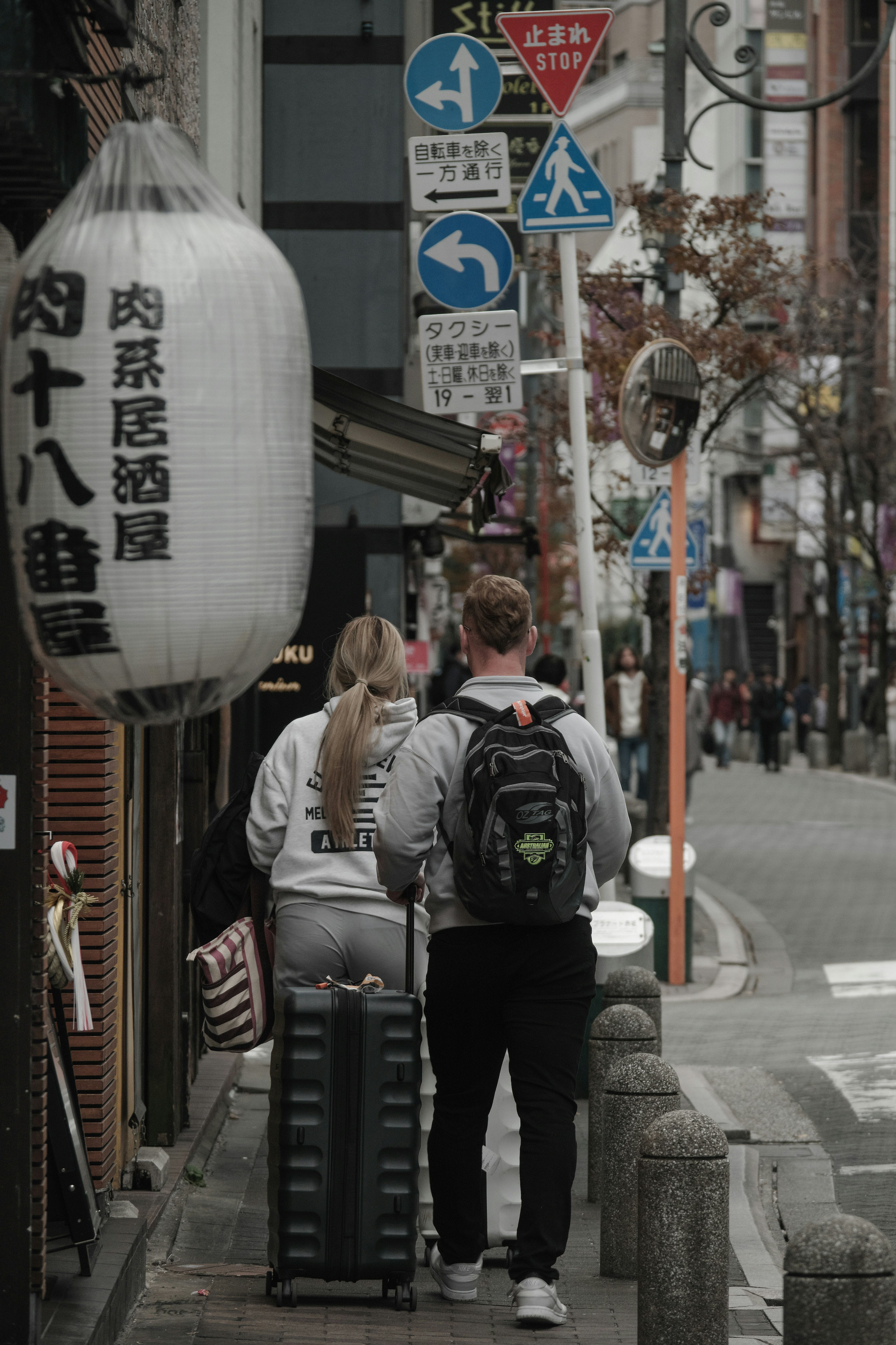 街を歩くカップルとキャリーケースがある風景の写真