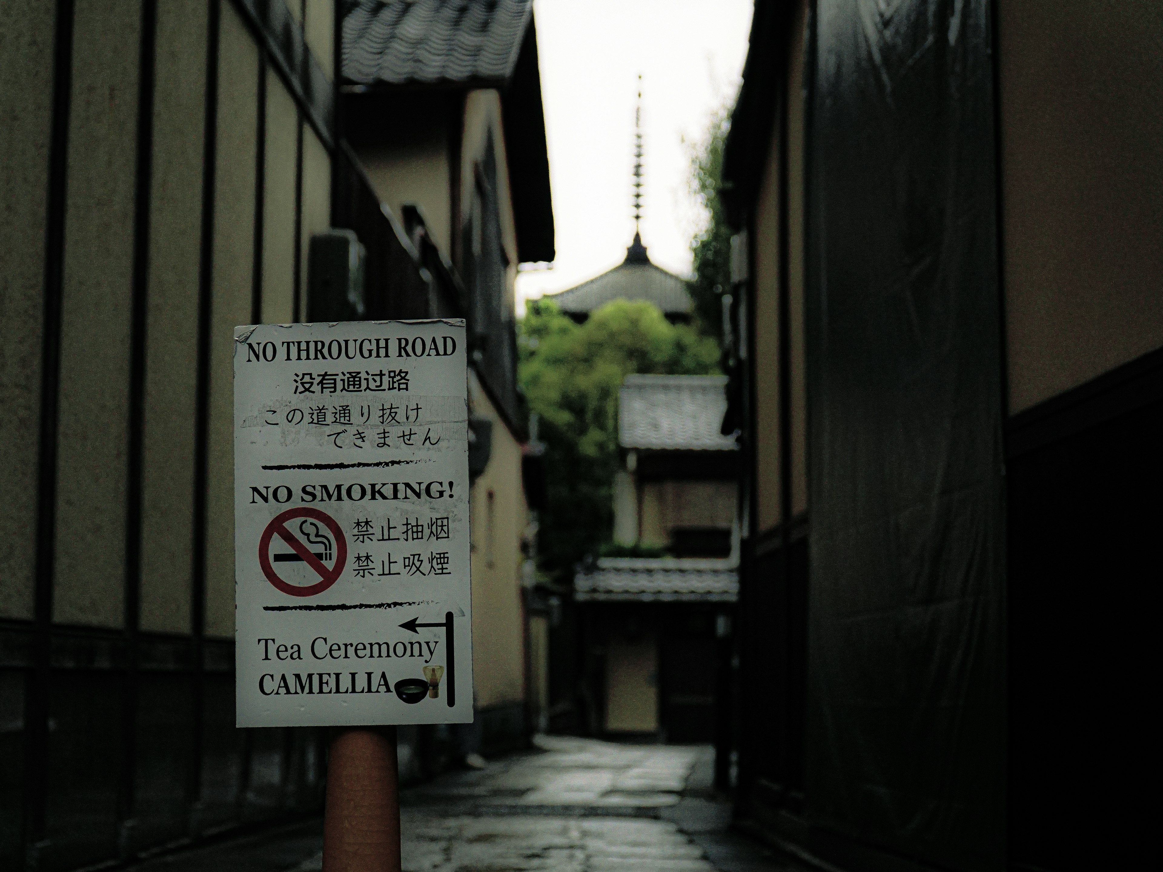 Vicolo stretto con un cartello di divieto di fumo e tempio sullo sfondo