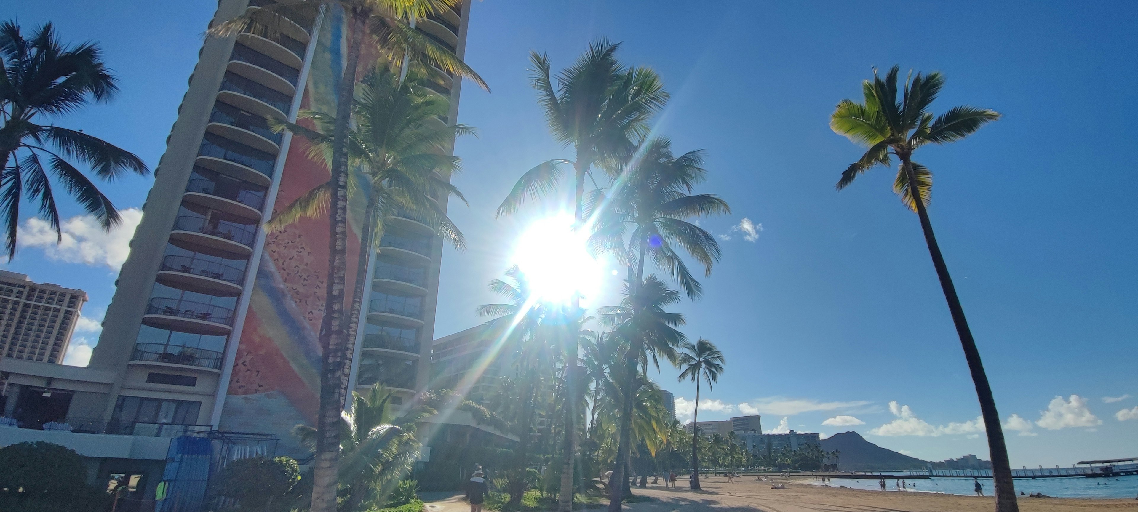 Hochhaus und Palmen am Strand mit strahlender Sonne