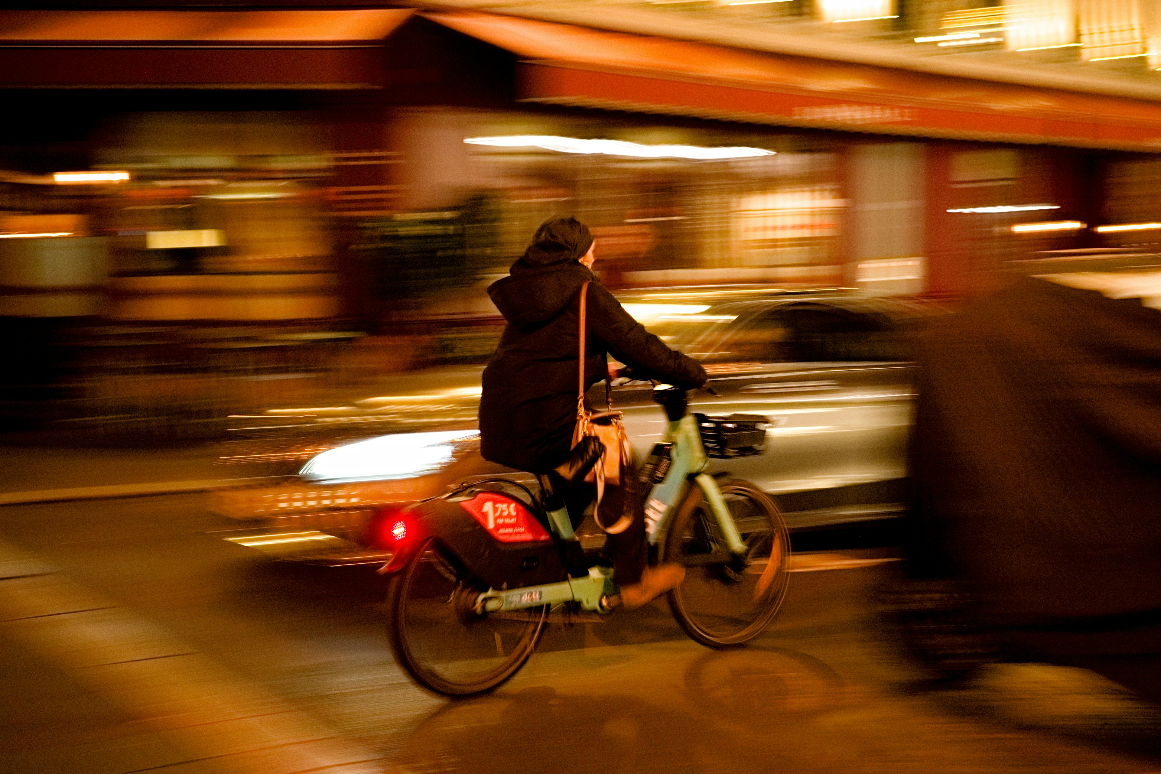 A person riding a bike swiftly through a city at night with blurred lights