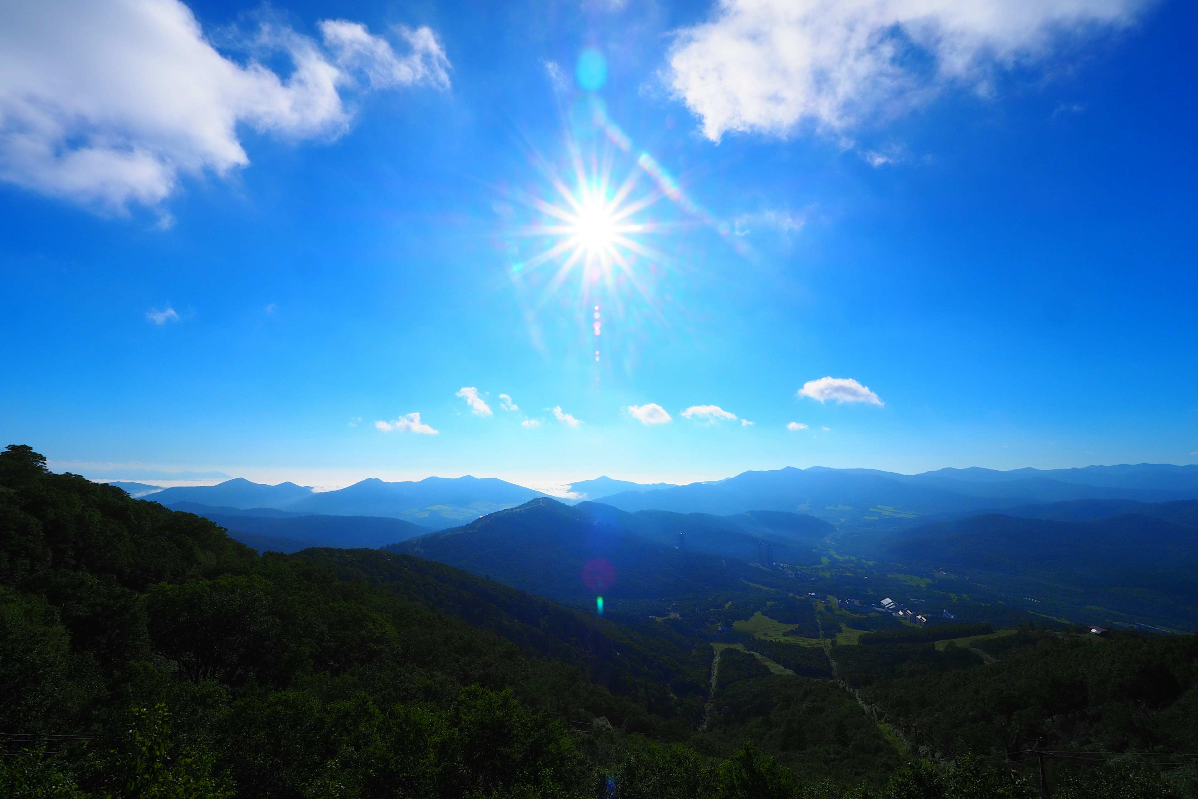 Paysage montagneux sous un ciel bleu clair avec un soleil brillant