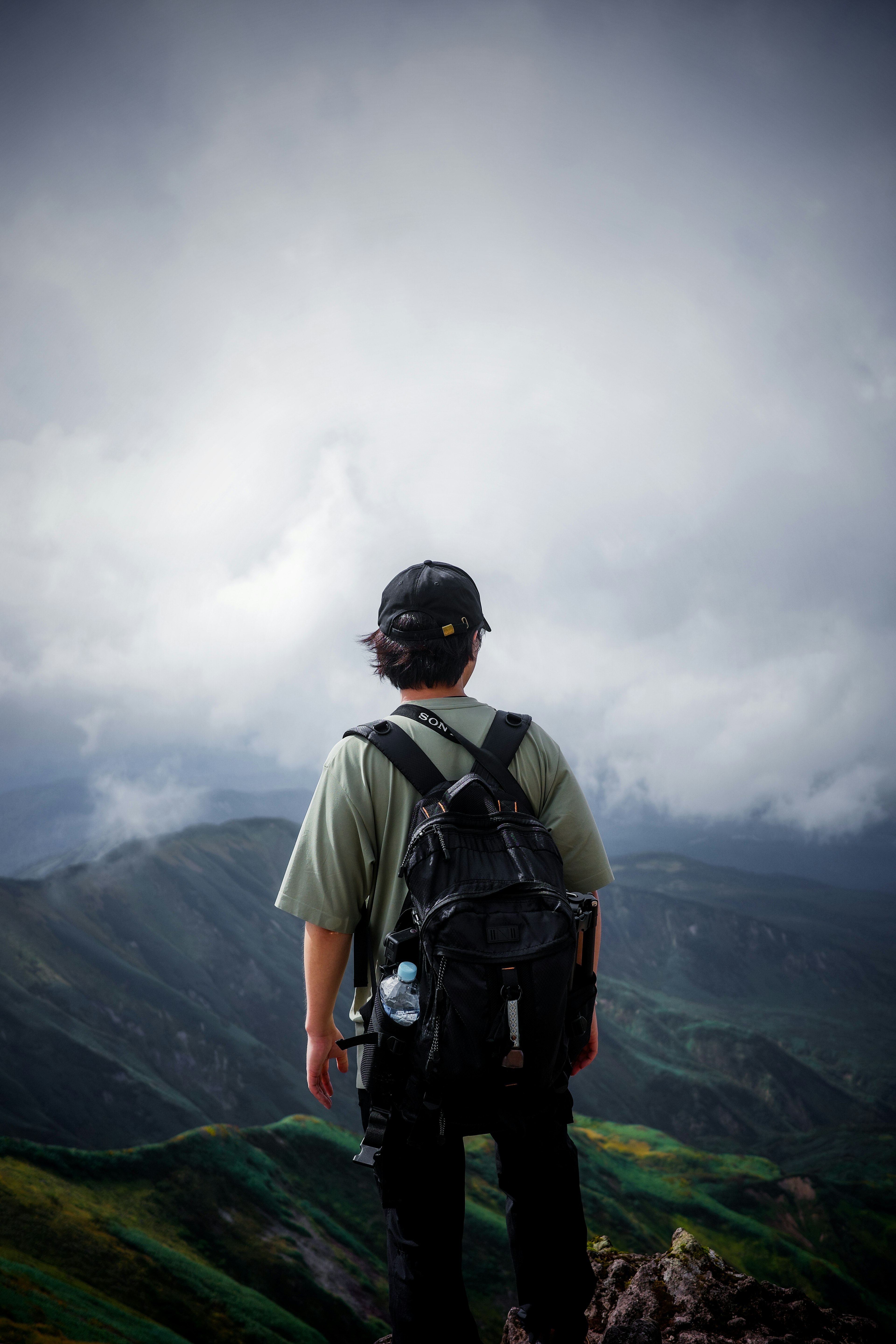 Wanderer steht auf einem Berggipfel und schaut in die Ferne