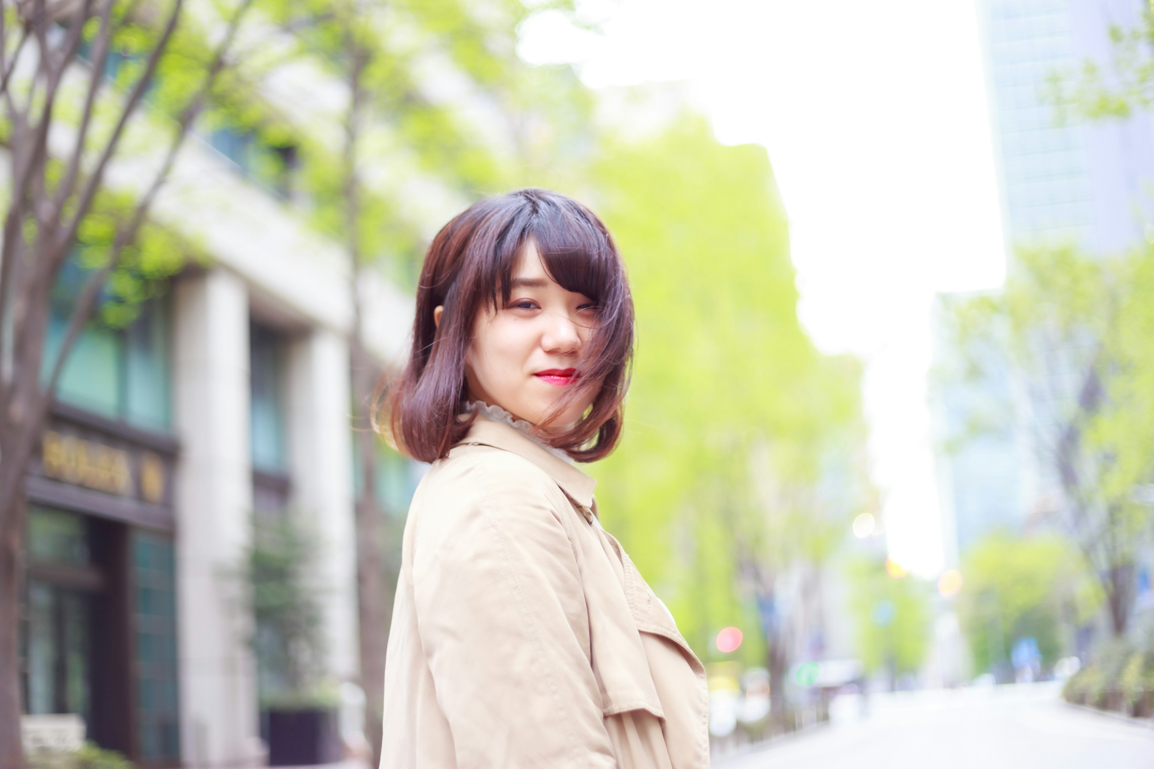 Mujer sonriendo en la ciudad con árboles verdes y fondo brillante