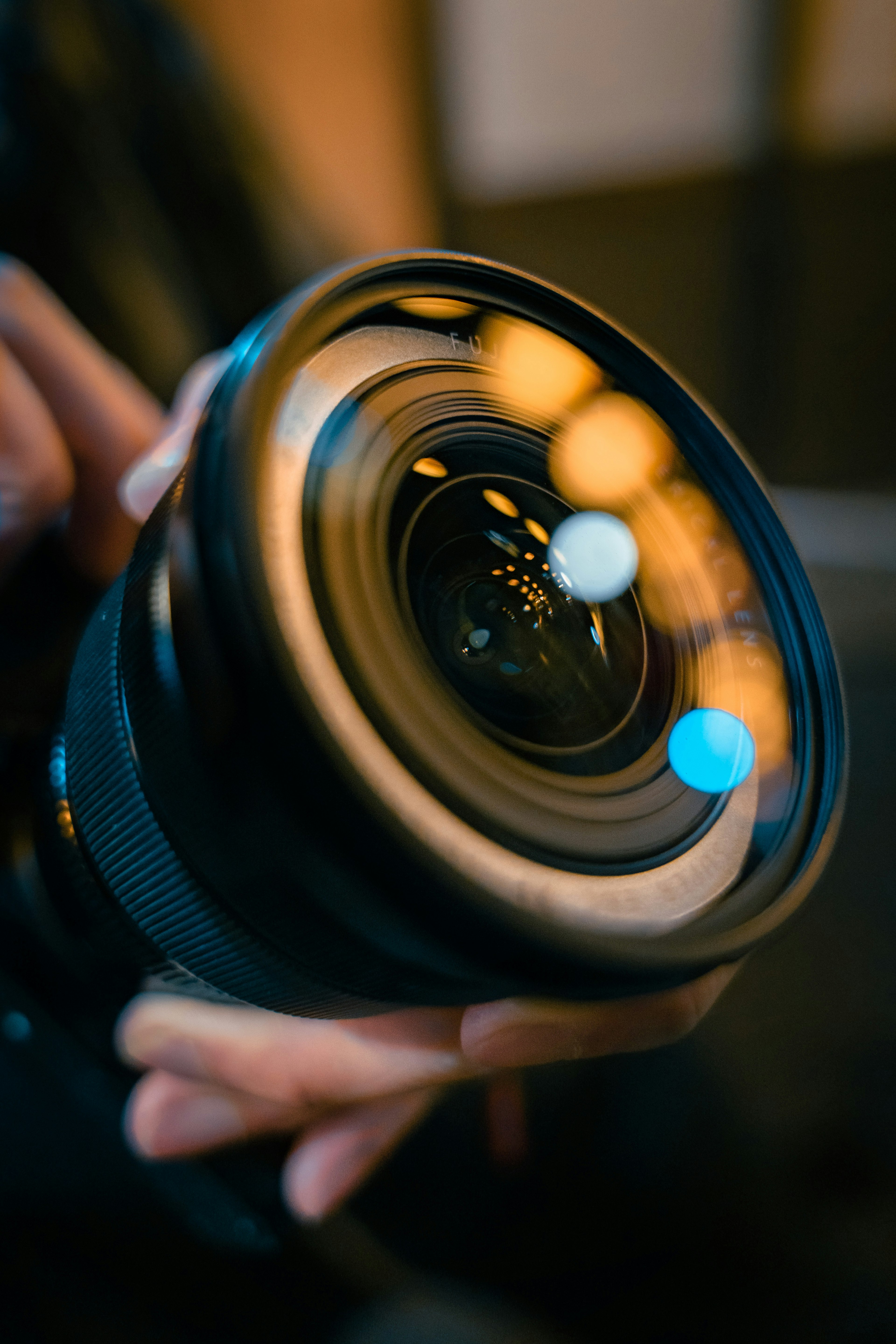 Close-up of a camera lens held in hand showcasing details and light reflections