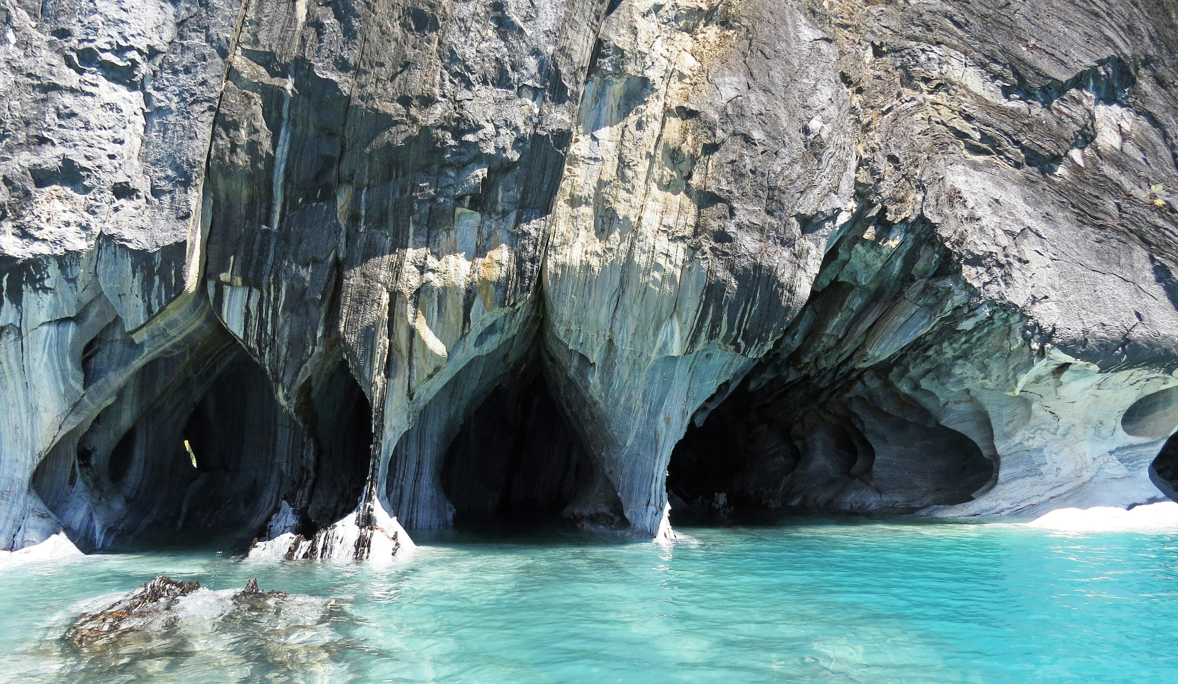 Pemandangan indah air biru dan gua batu di sepanjang pantai