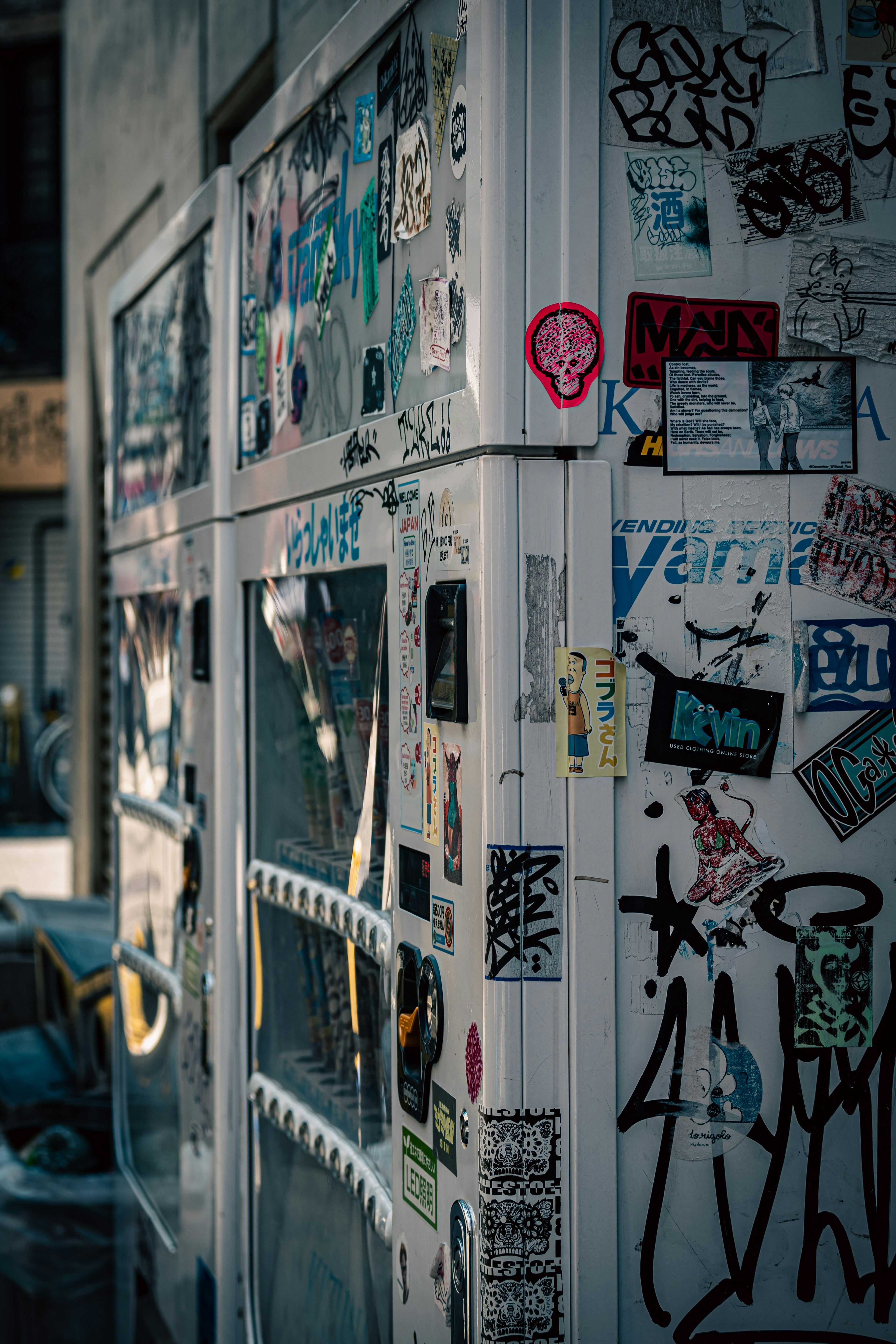 Esquina de un refrigerador cubierto de varios adhesivos y grafitis