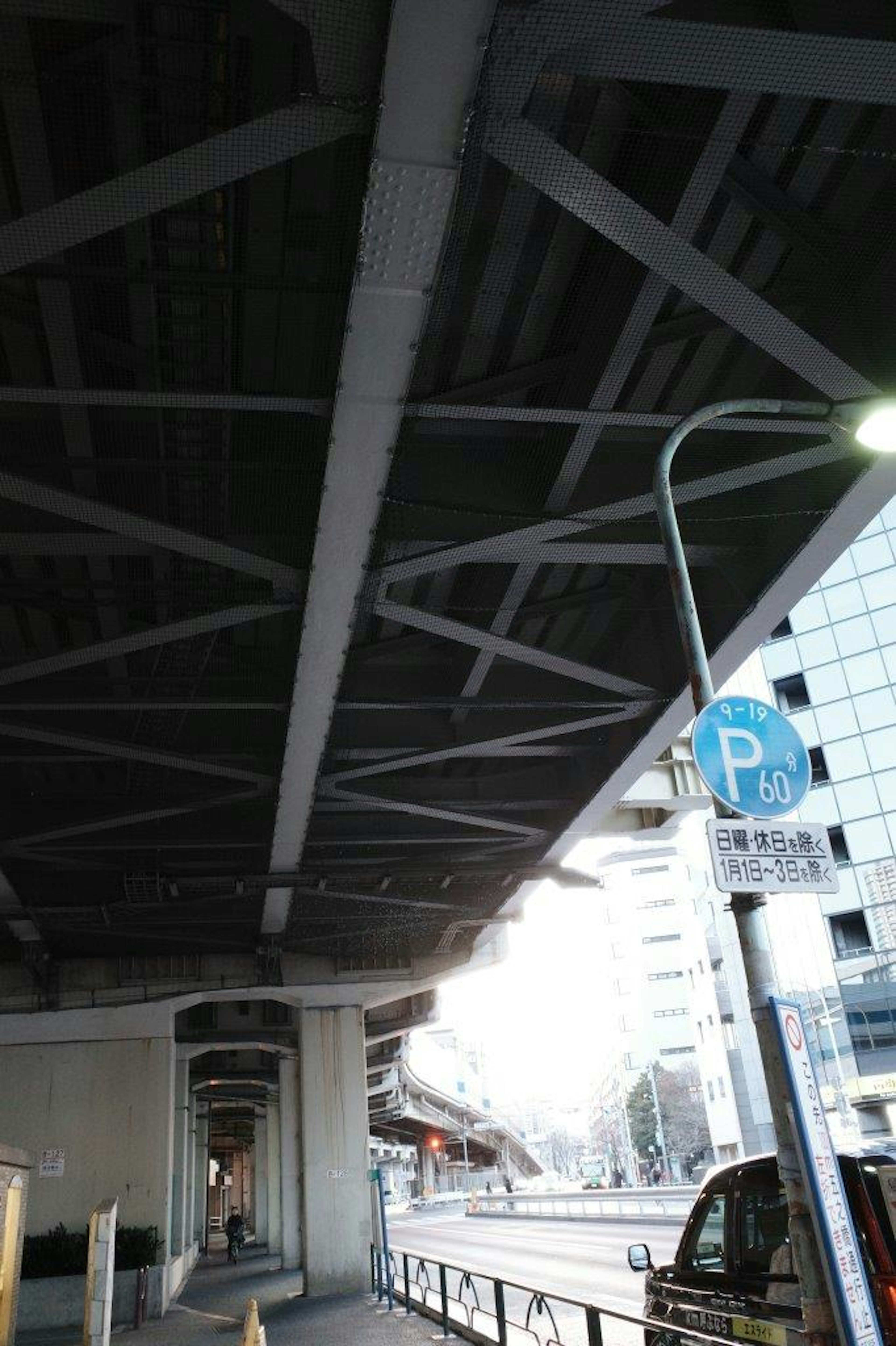 Straße und Parkzeichen unter einer erhöhten Brücke