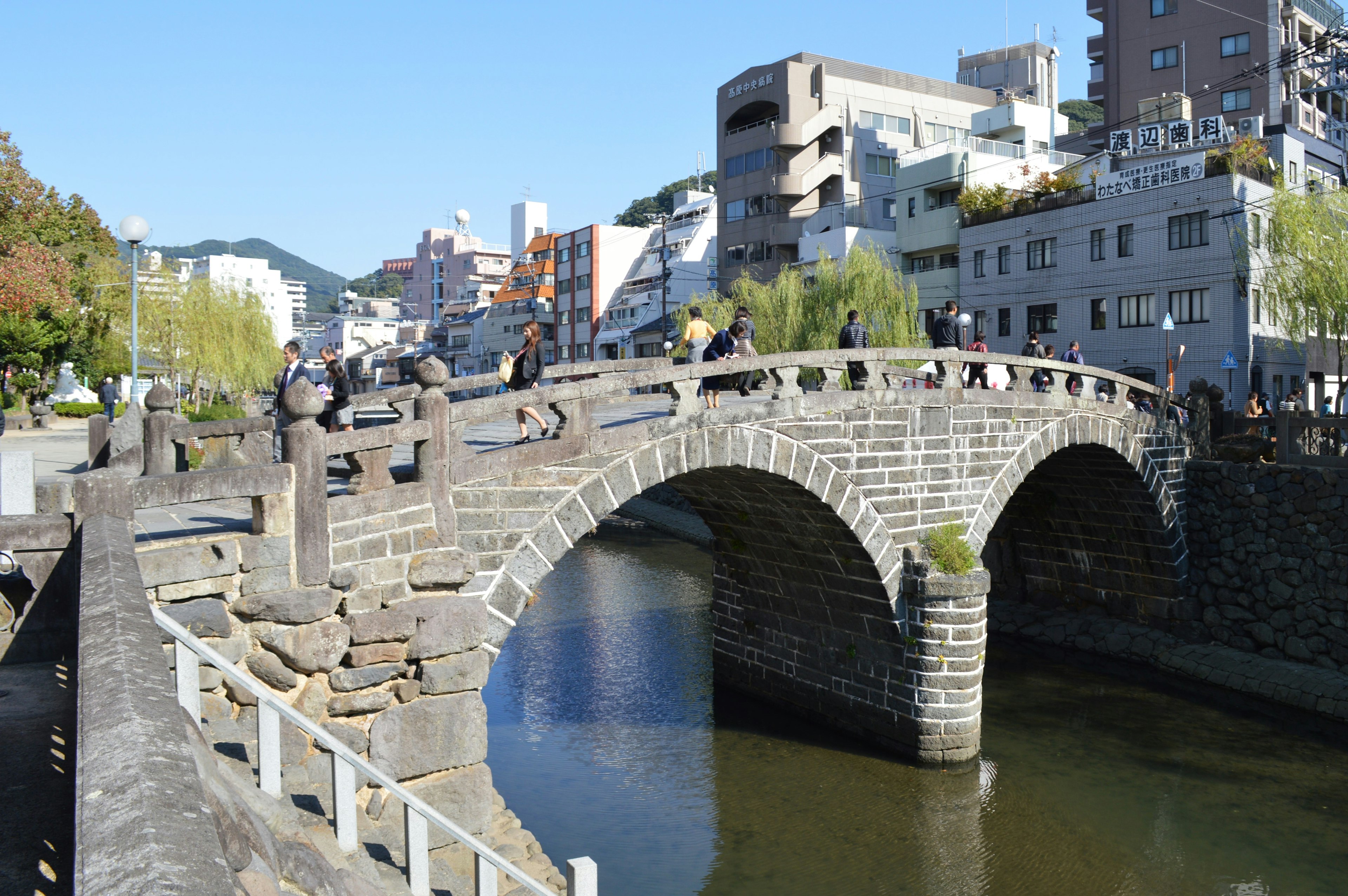 Puente de piedra histórico con edificios circundantes y cielo azul claro