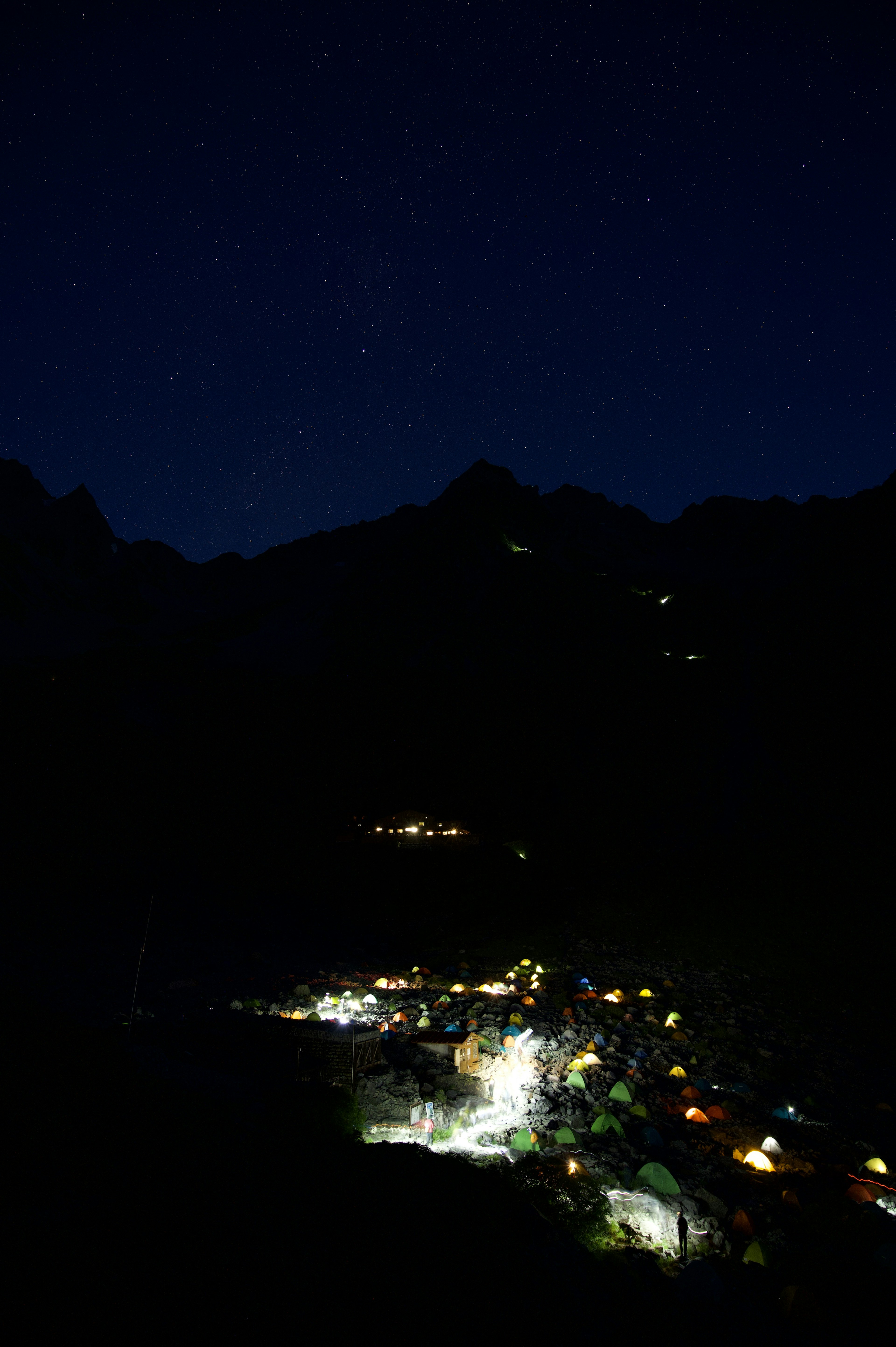 Un paysage montagneux la nuit avec des étoiles brillantes et des lumières d'un village