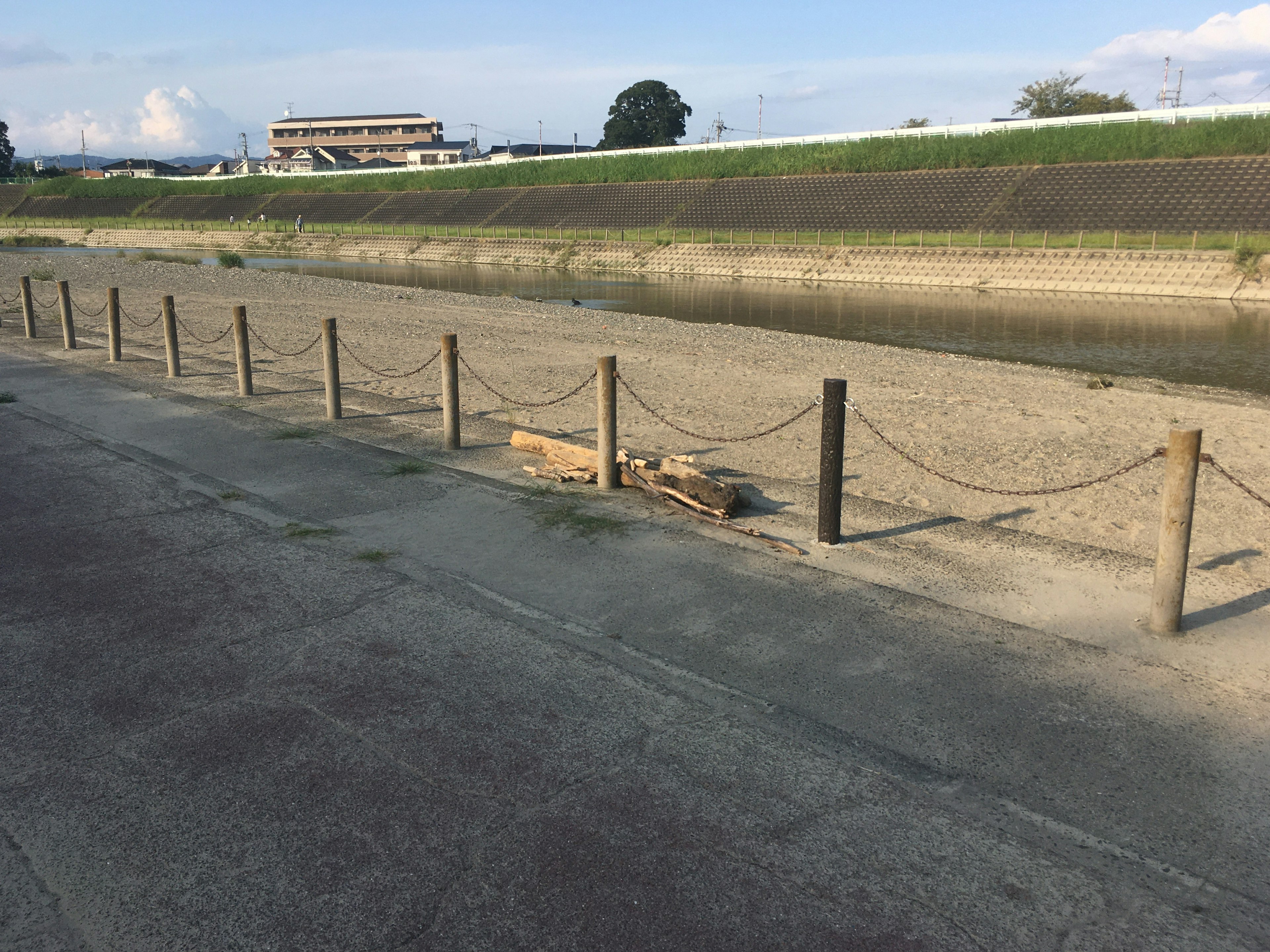 Cerca de madera a lo largo de una ribera con suelo seco y edificios lejanos