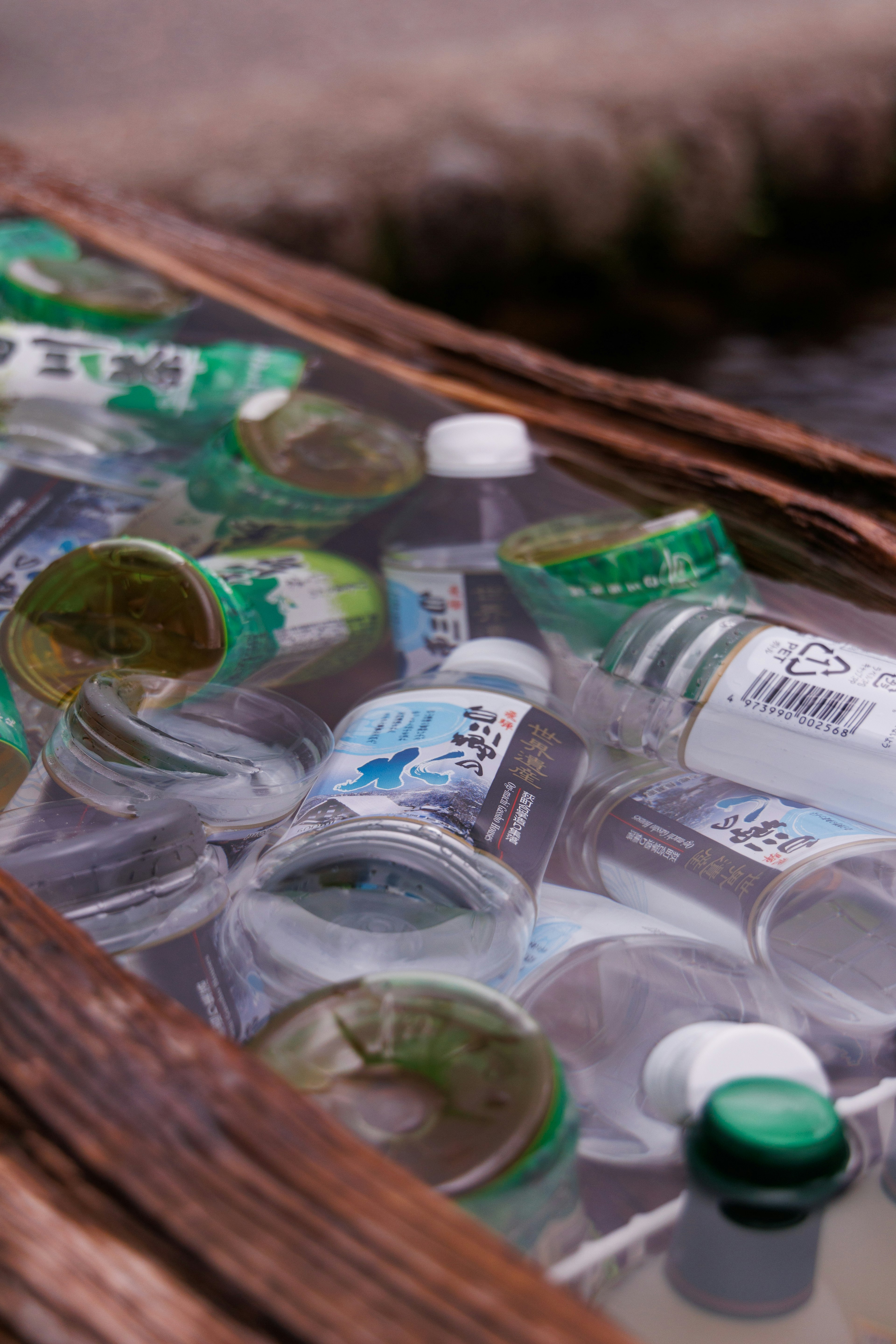 Various beverage bottles floating in water with a wooden frame