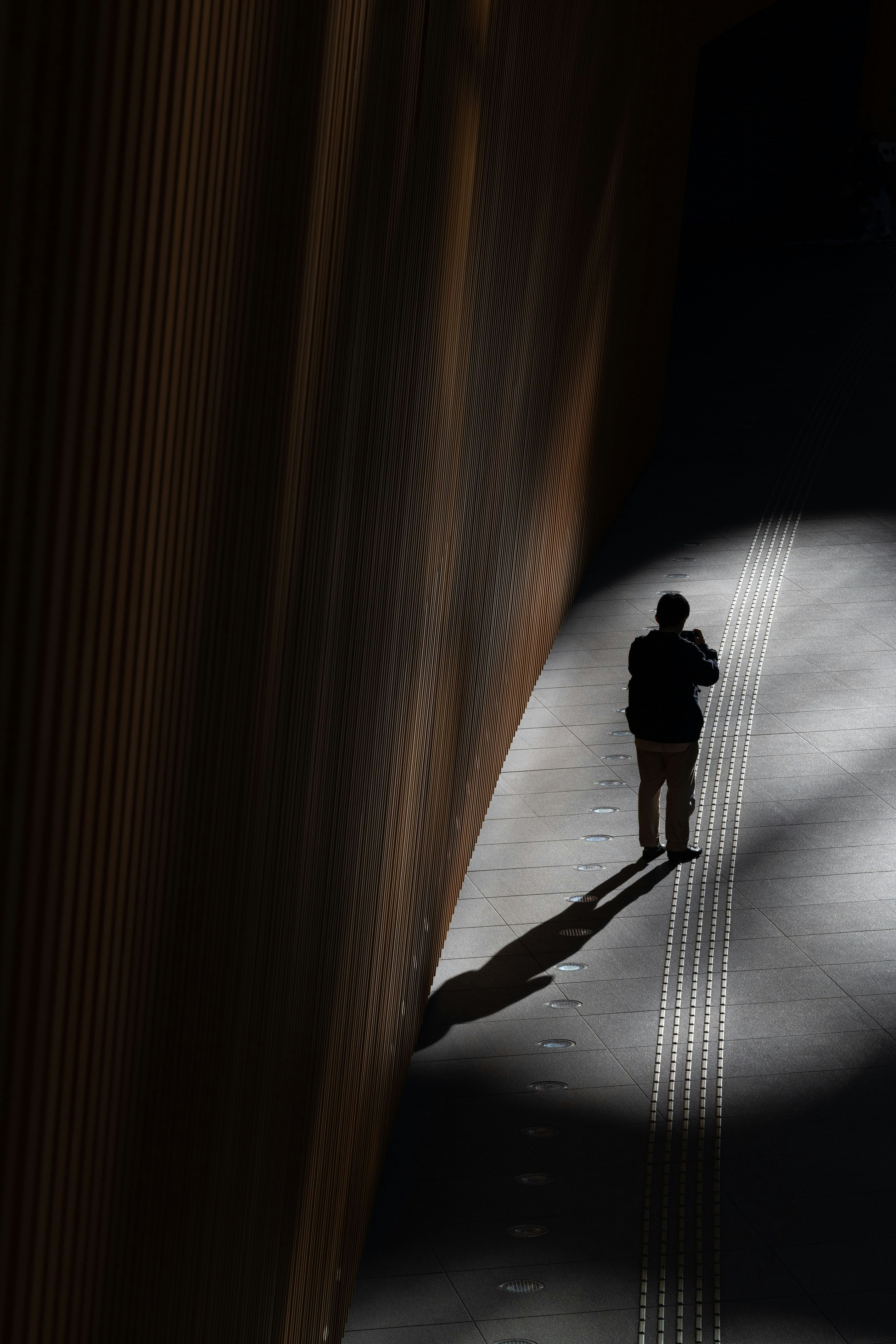 Silueta de una persona caminando en sombras con contraste de luz