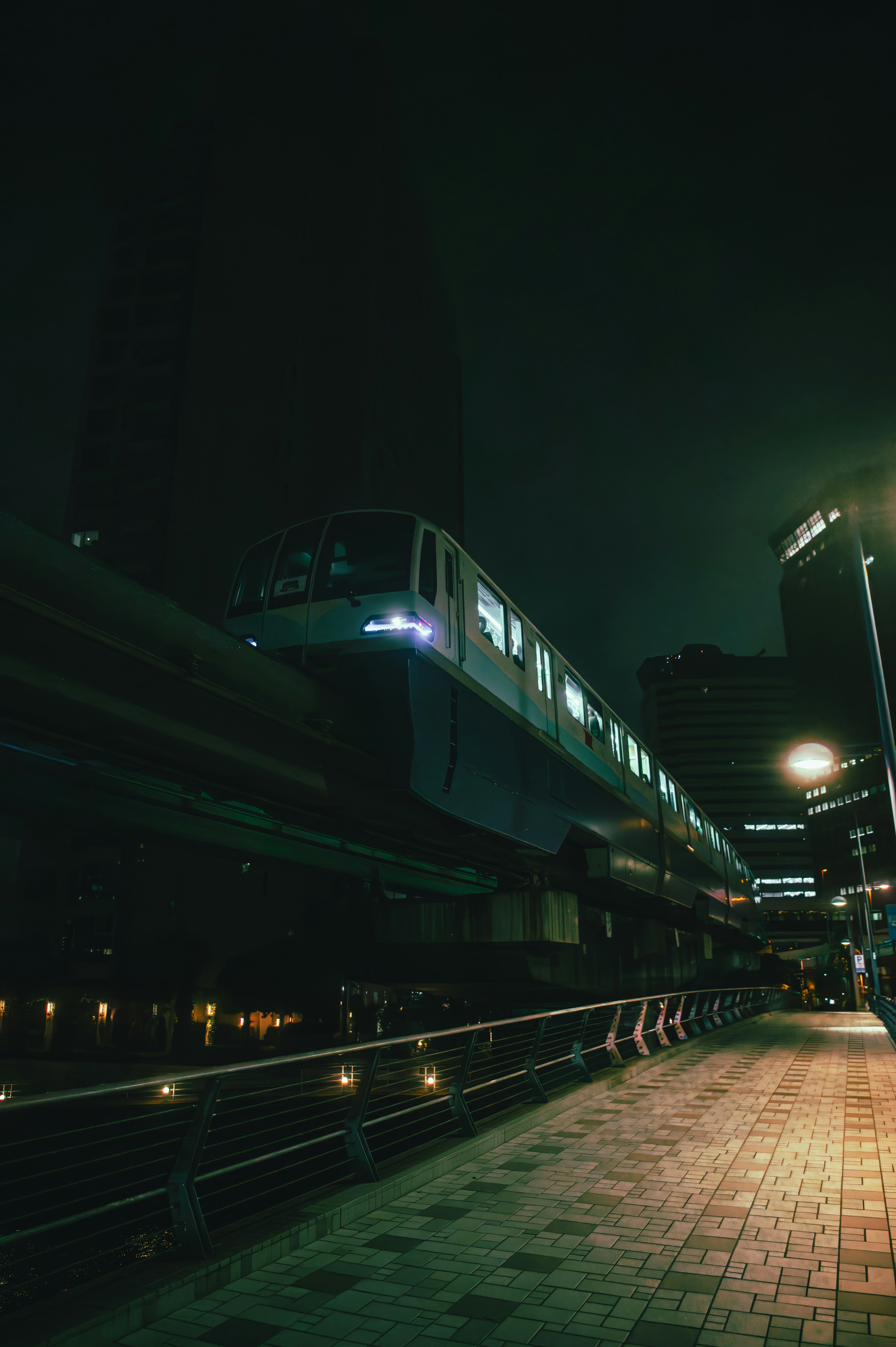 Monorail gliding above a dimly lit urban landscape at night