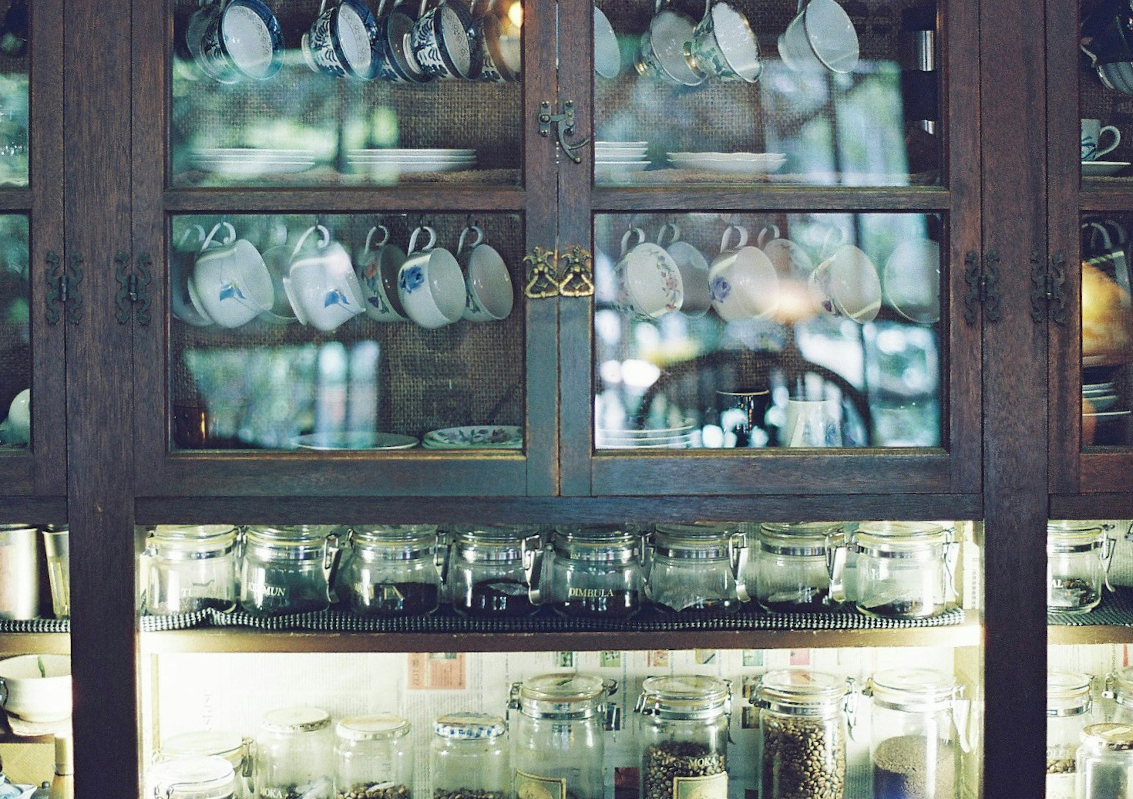 Glass-front cabinet displaying neatly arranged cups and jars