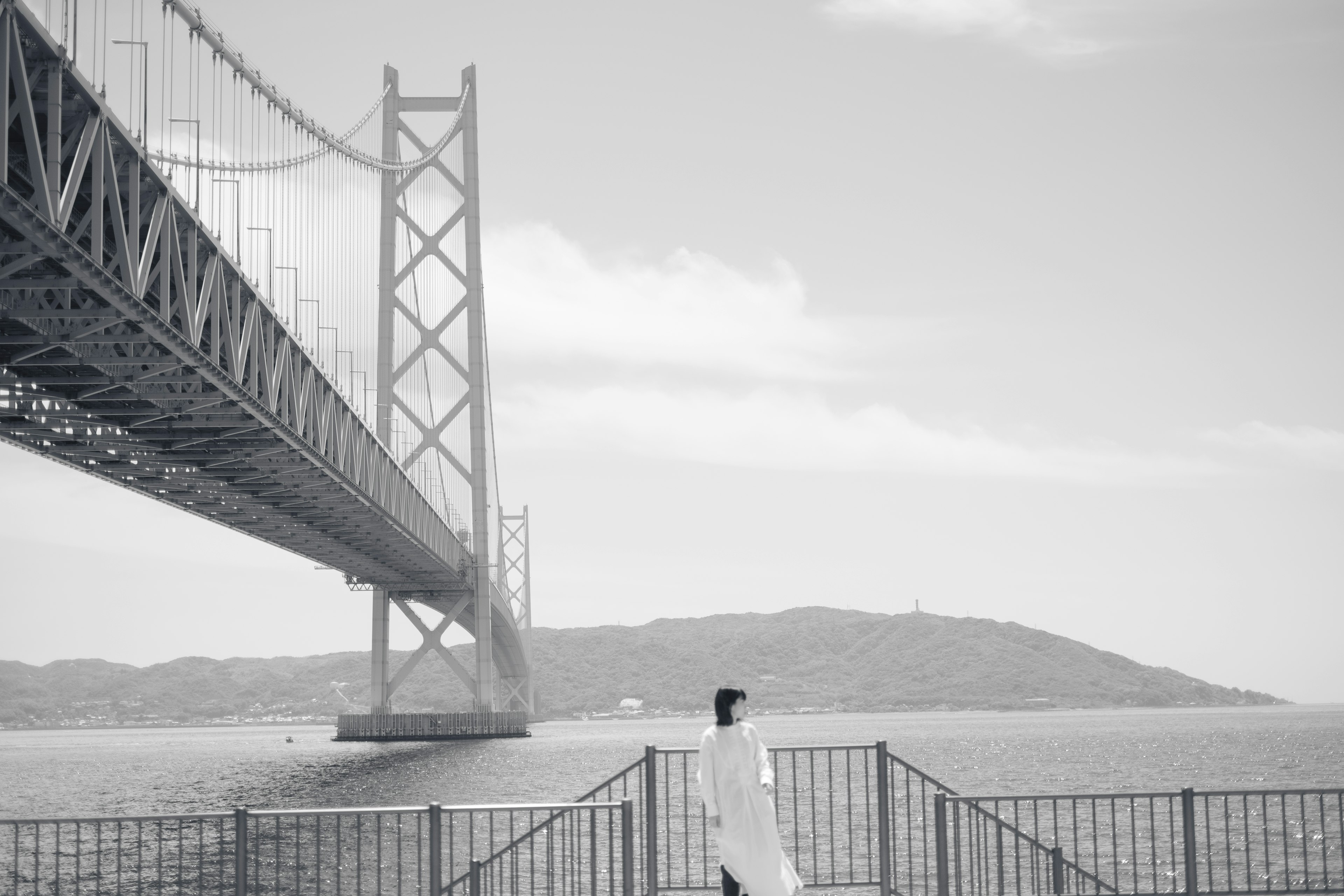 A woman in white walking near a bridge over the Seto Inland Sea