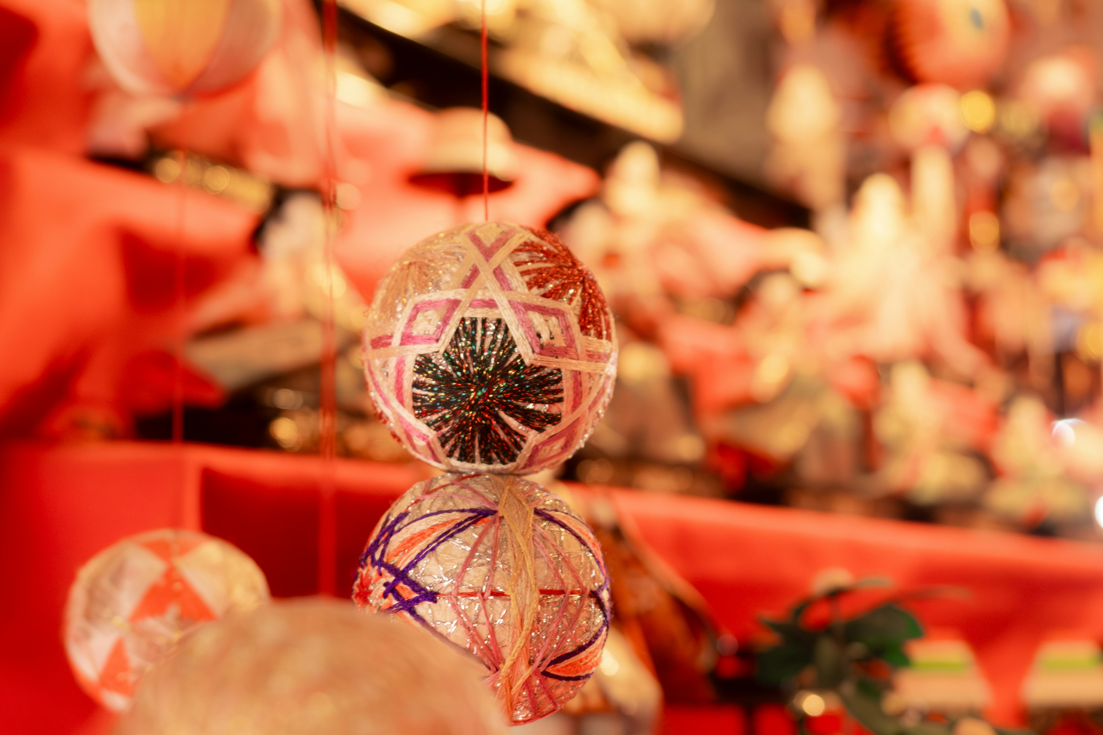 Boules décoratives colorées suspendues dans un espace orné de décorations rouges