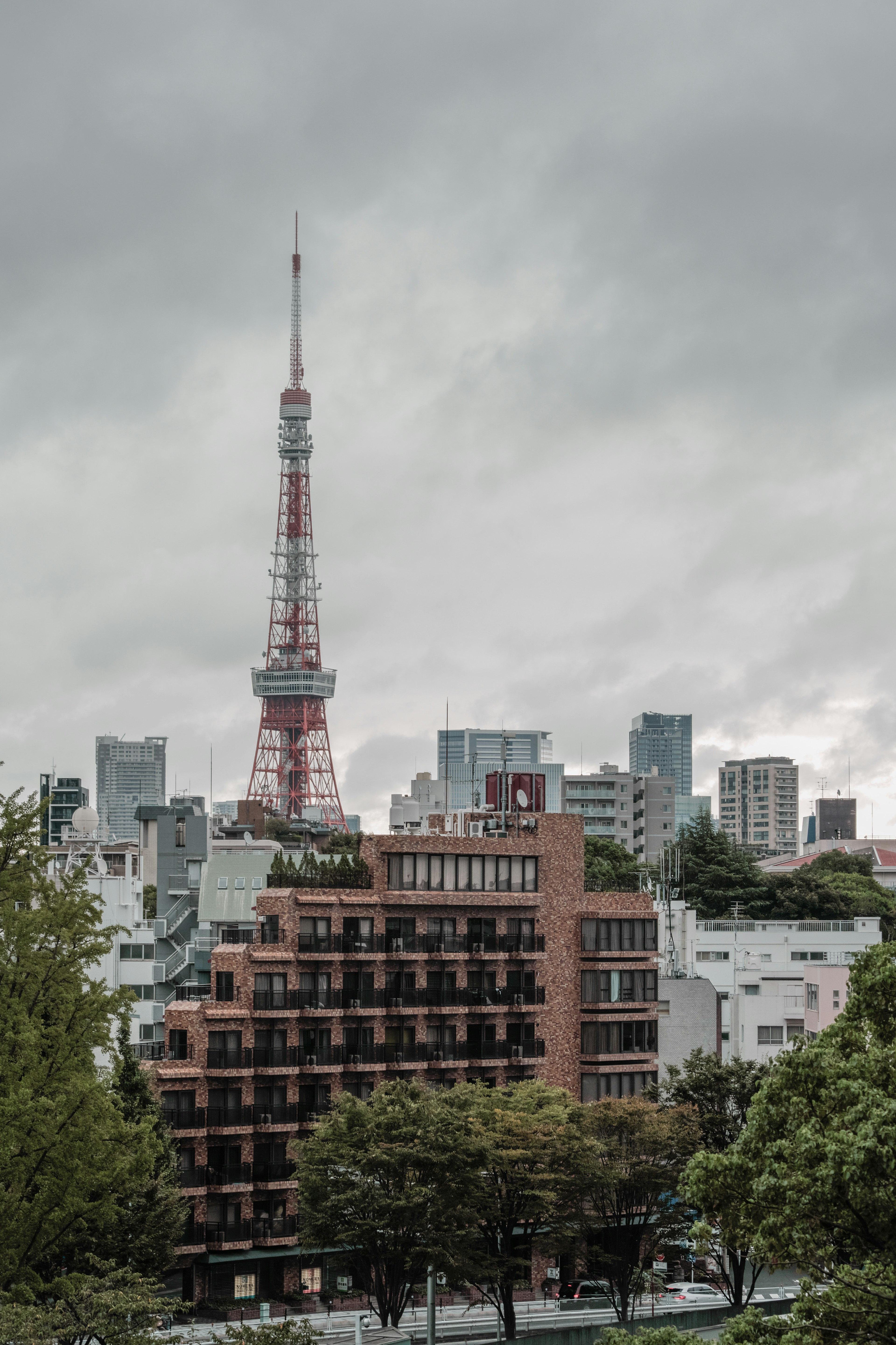 東京塔在陰雲密布的天空下耸立，周圍是城市建築