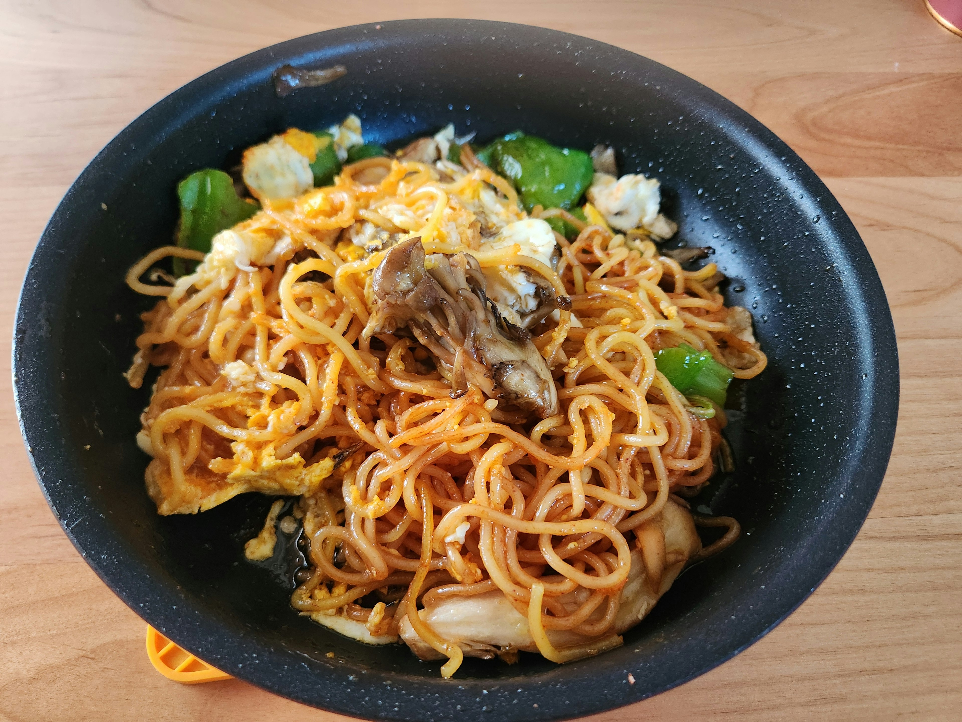 Fried noodles with vegetables served in a black bowl