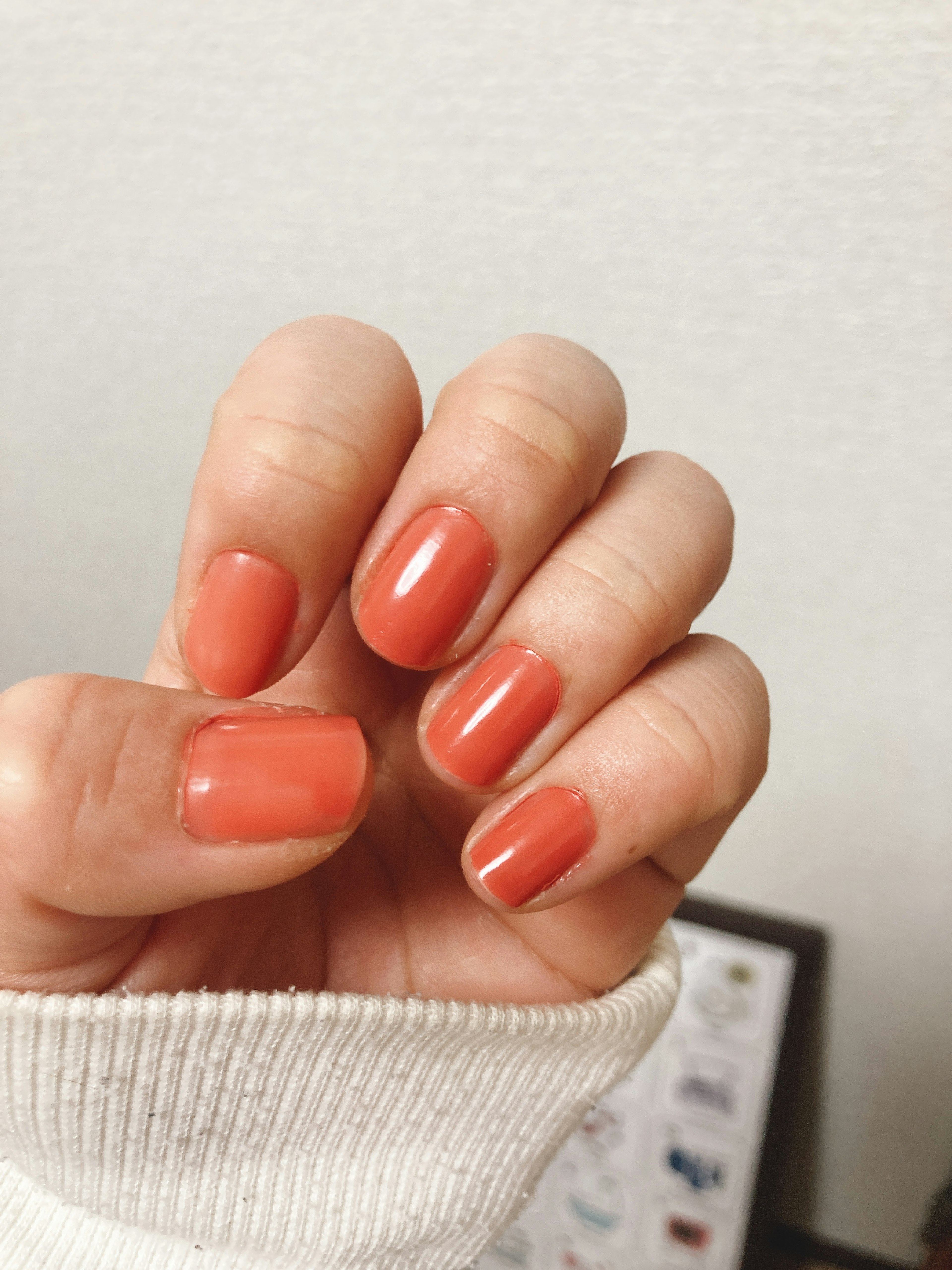 Close-up of a hand with coral nail polish on fingernails