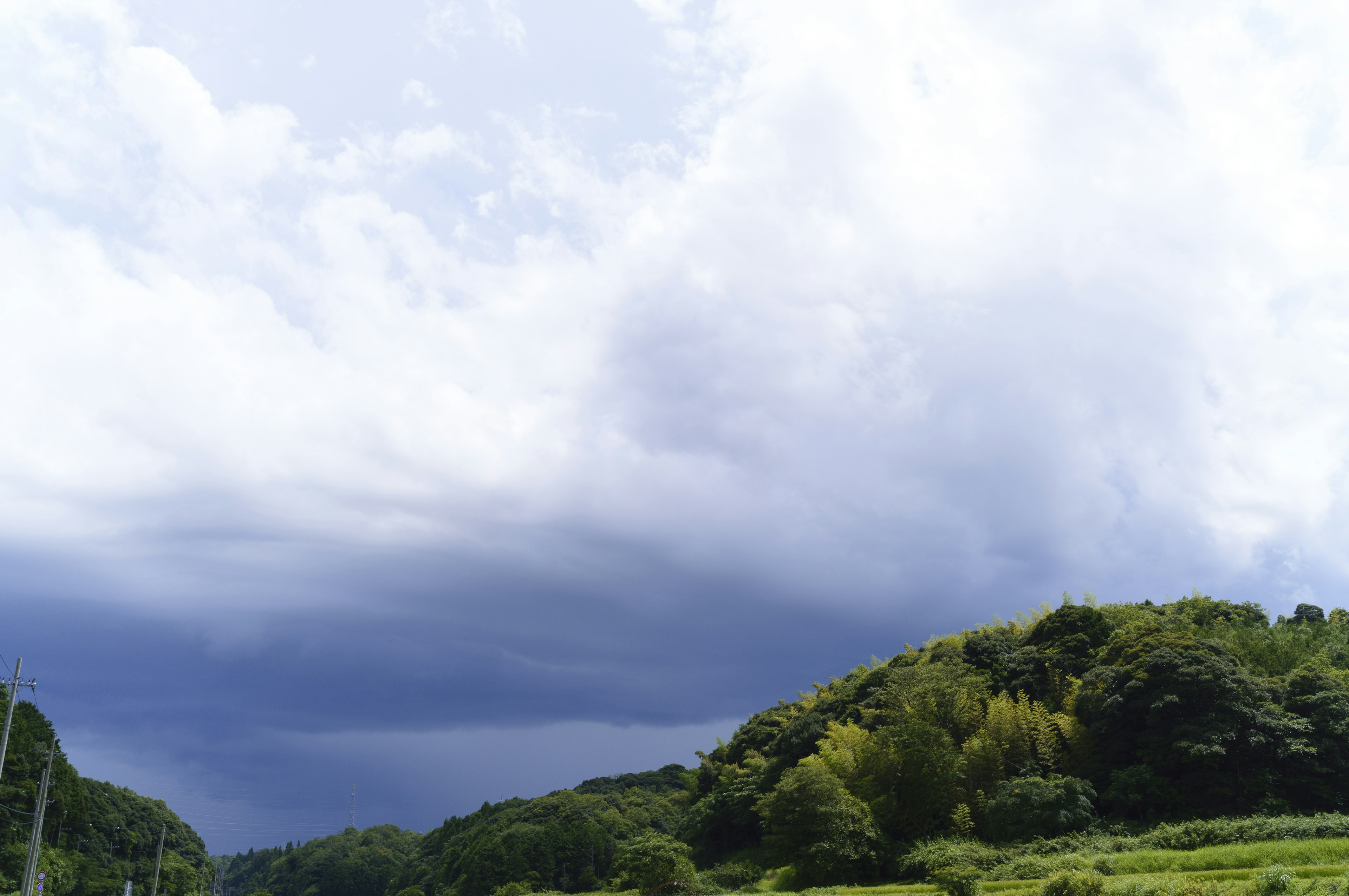 Pemandangan langit biru dengan awan bukit hijau dan ladang rumput