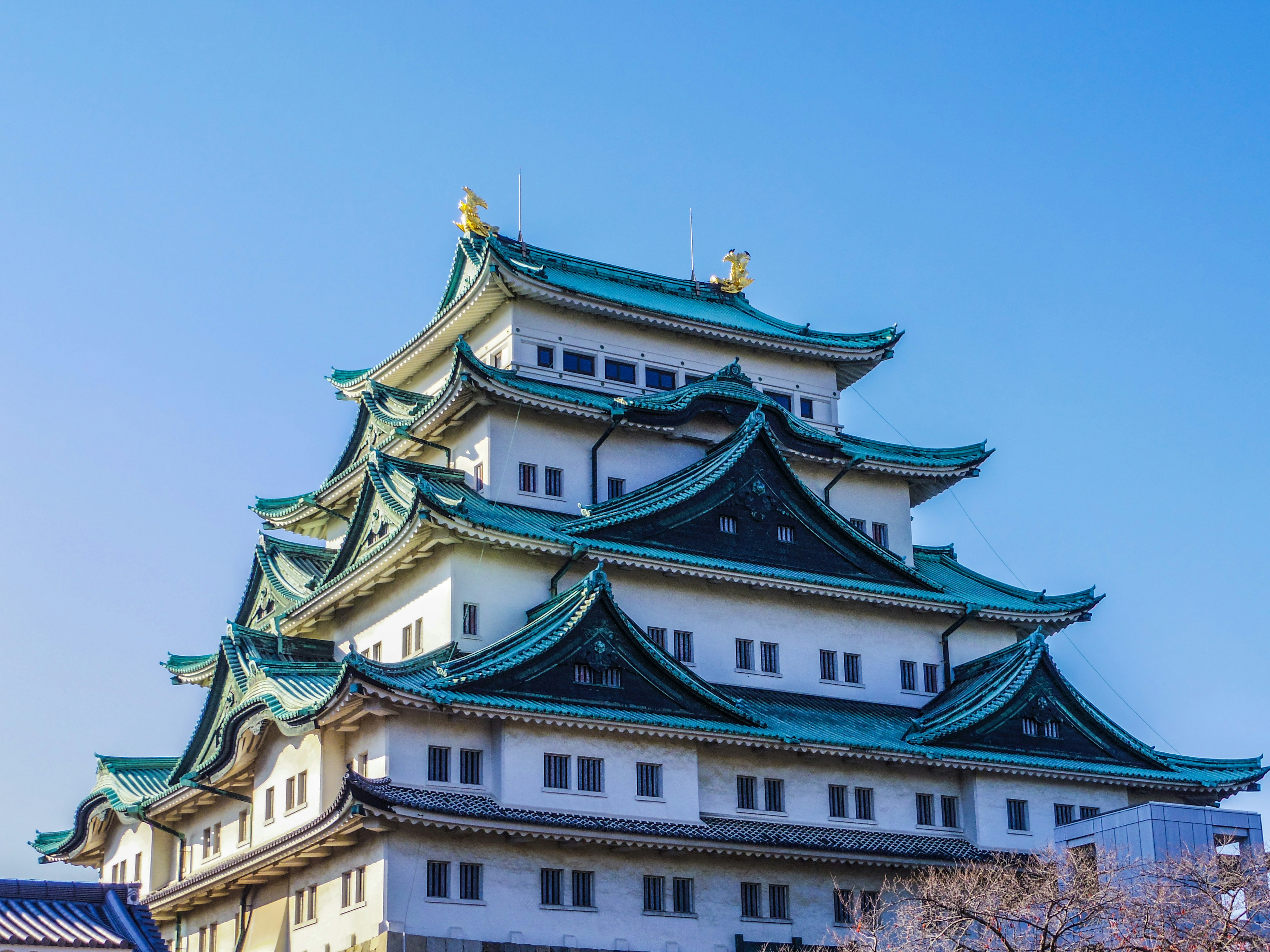 Nagoya-Schloss mit markanten grünen Dächern vor klarem blauen Himmel