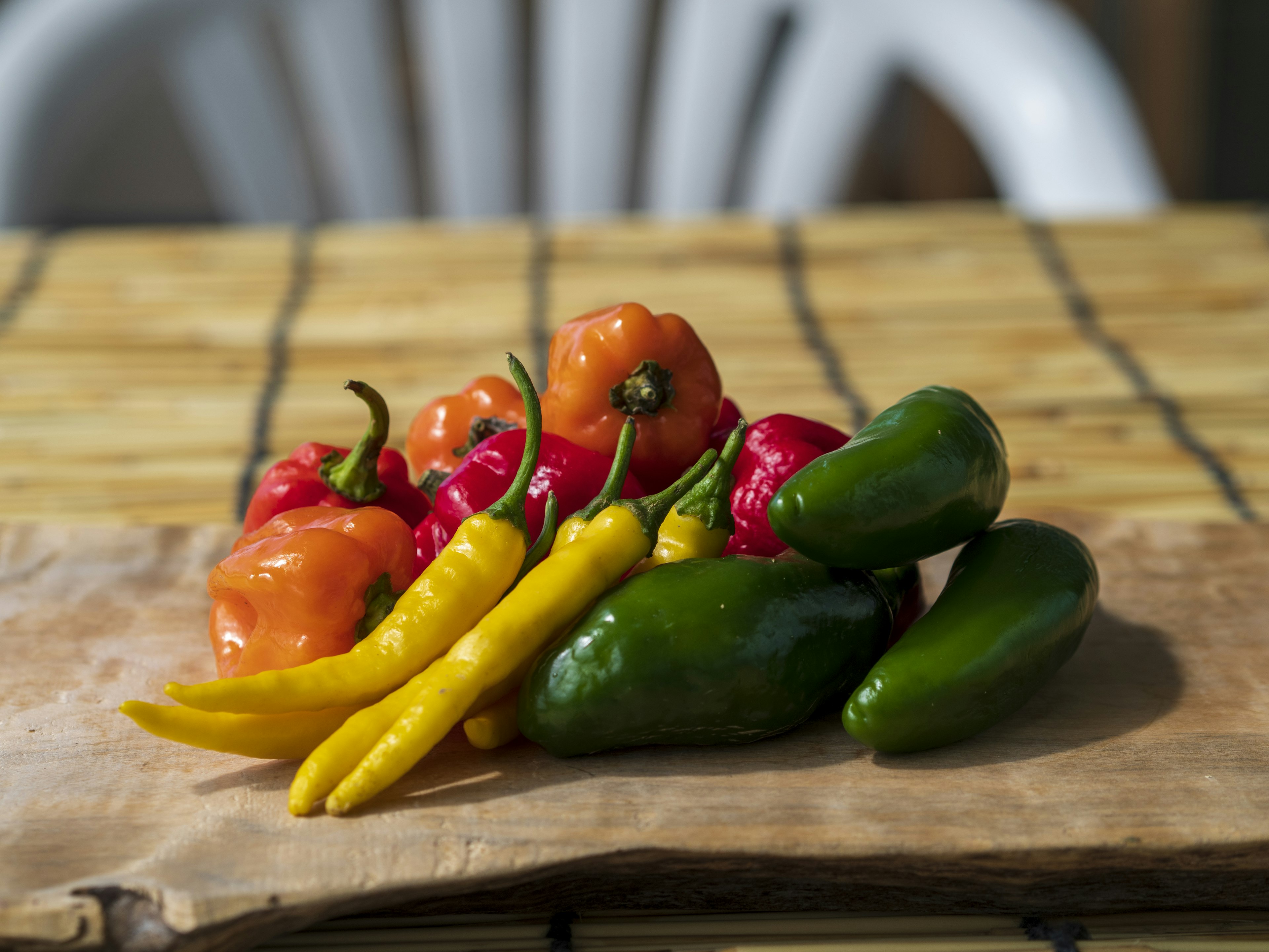 Eine bunte Auswahl an Paprika auf einem Holzbrett angeordnet