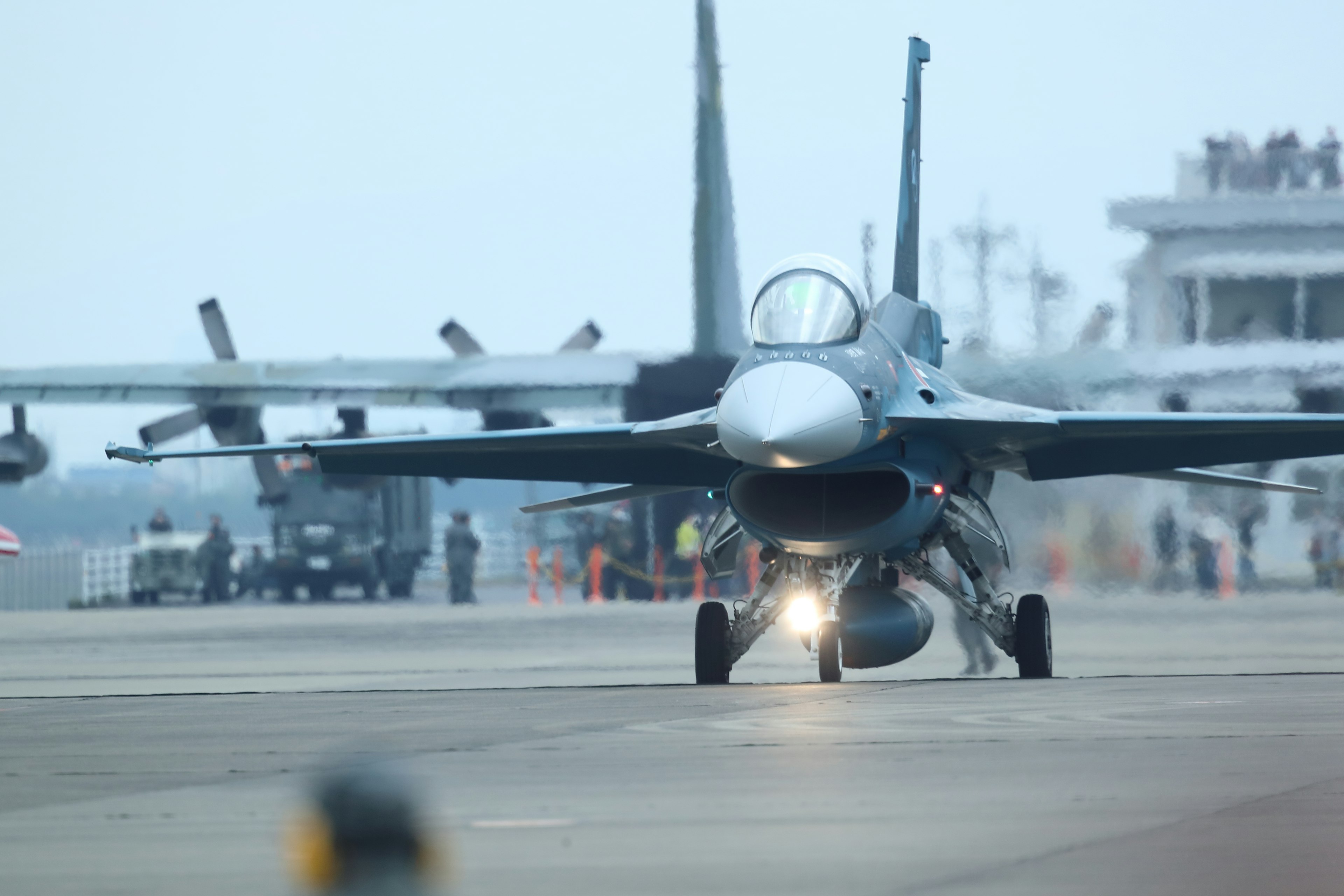 F-16 fighter jet on the runway with other aircraft in the background