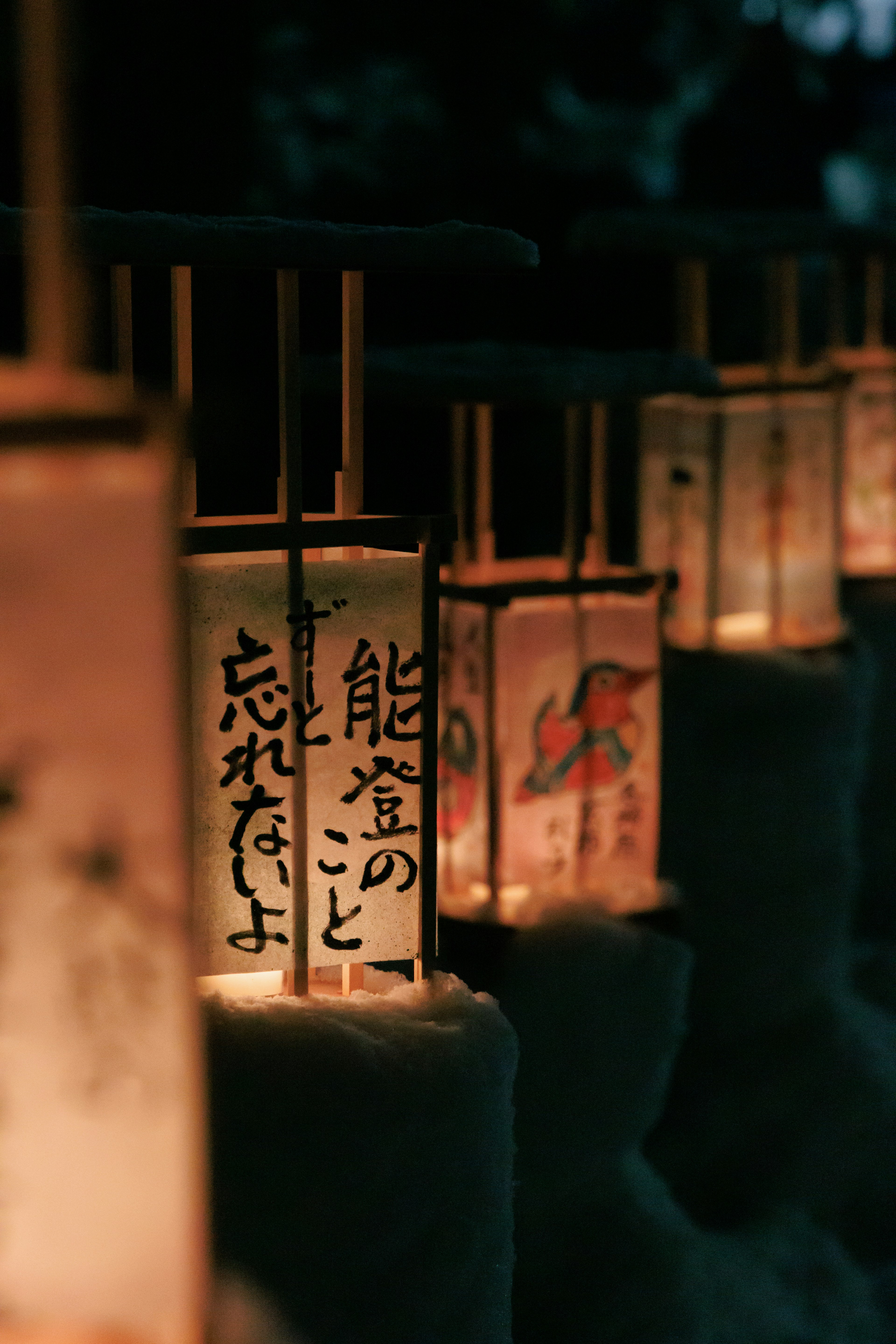 Row of lanterns with traditional Japanese characters illuminated at night