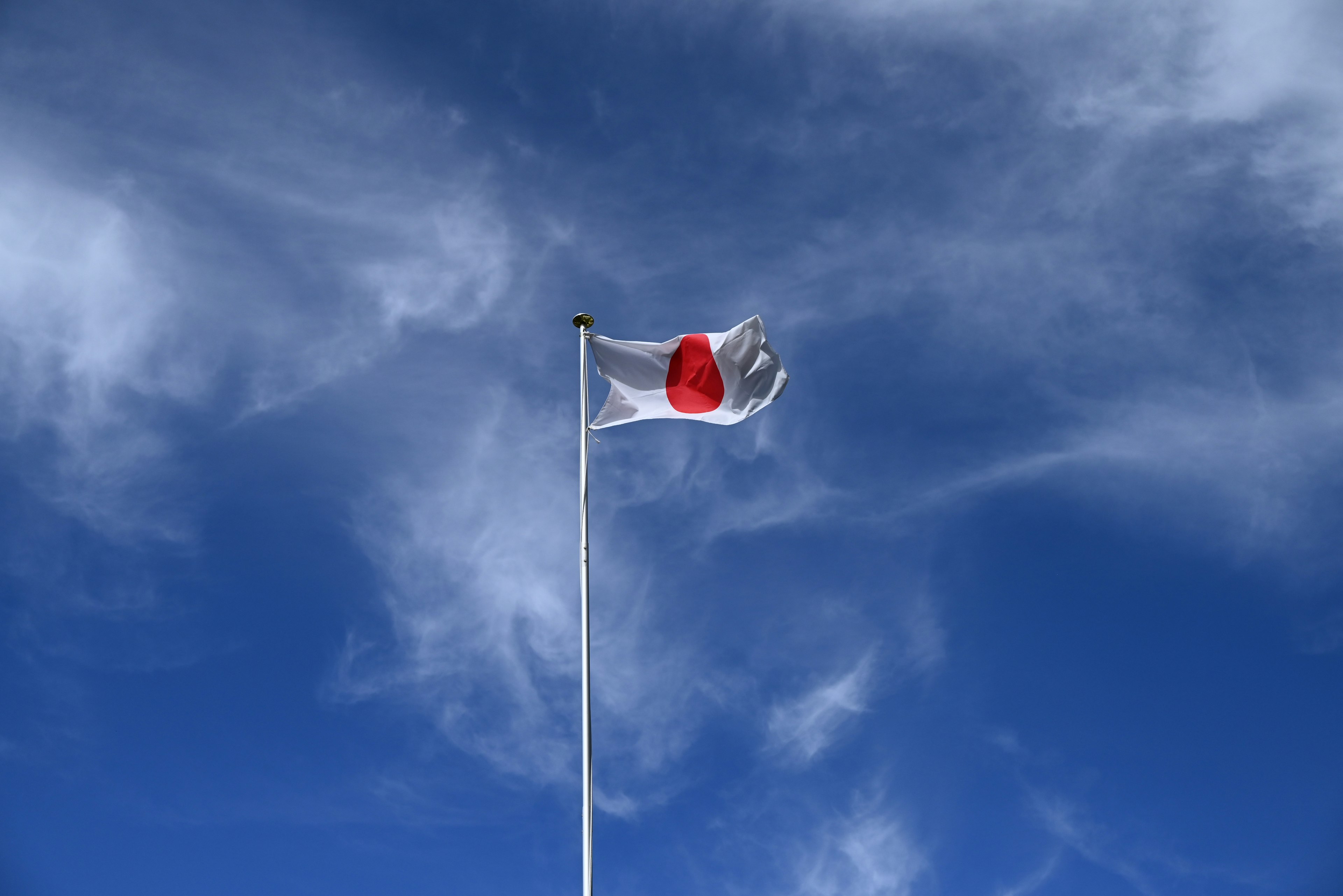 Bandera nacional de Japón ondeando bajo un cielo azul