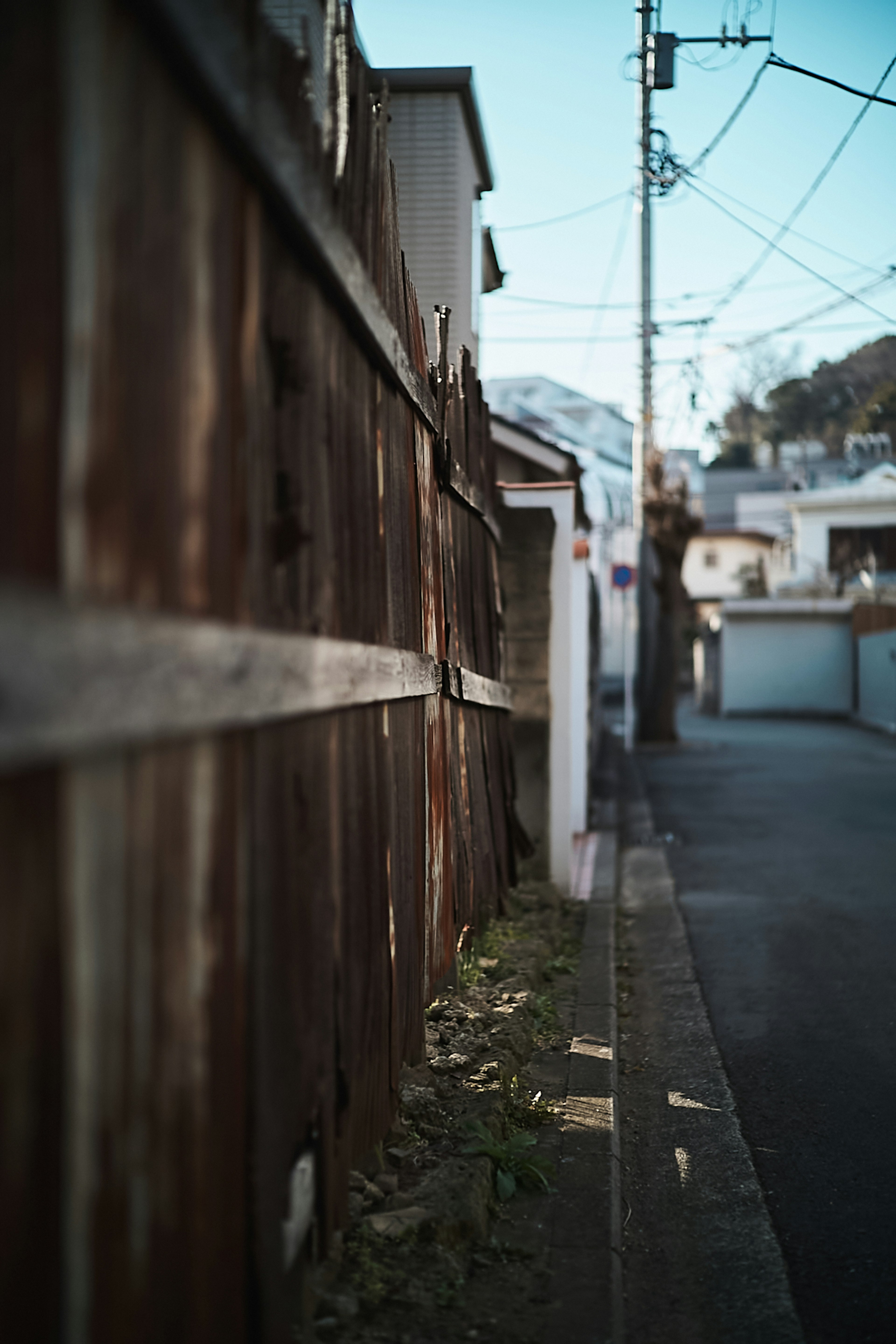 Una vista de una antigua cerca de madera junto a una calle estrecha