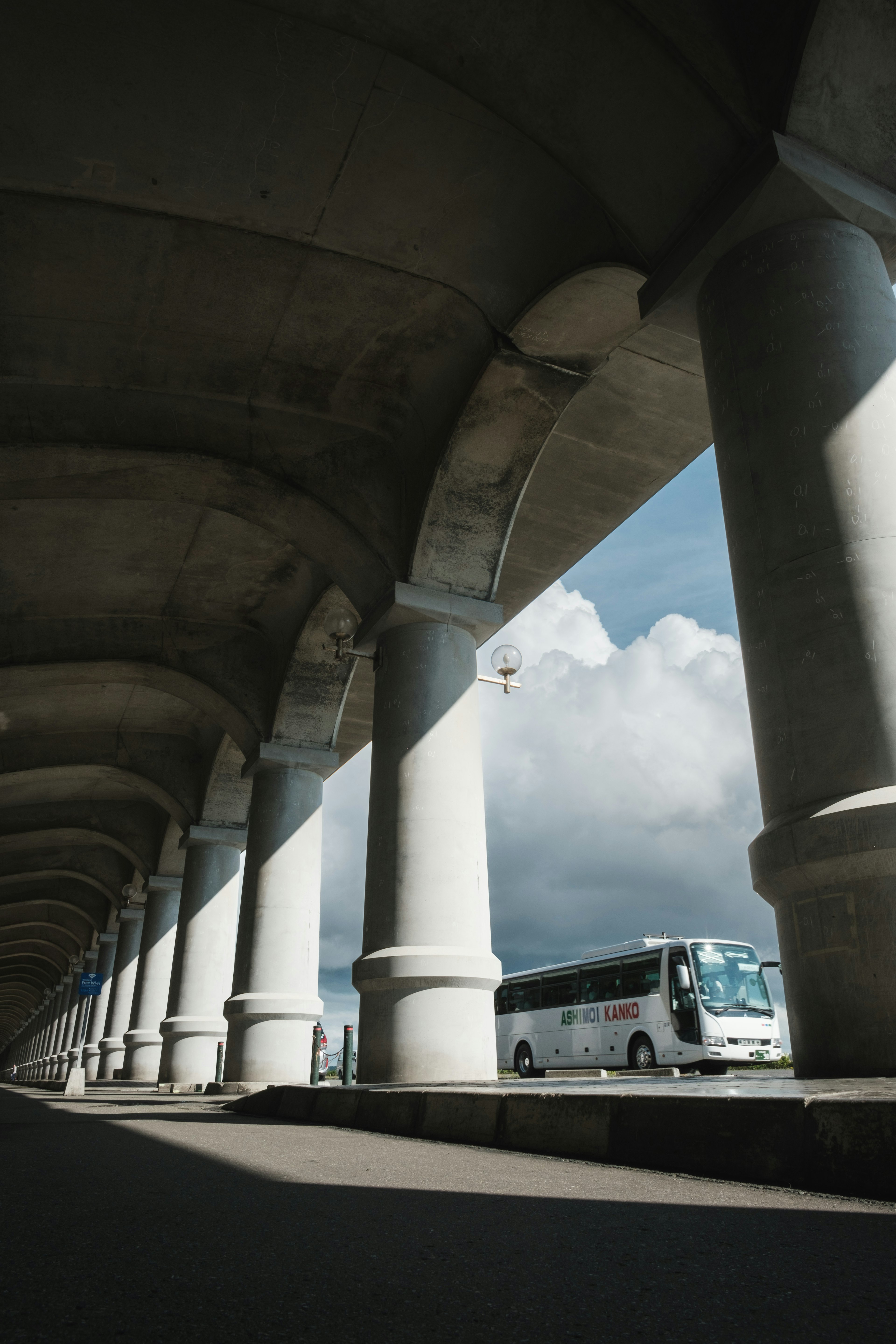 Bus parked under a series of columns with a blue sky backdrop