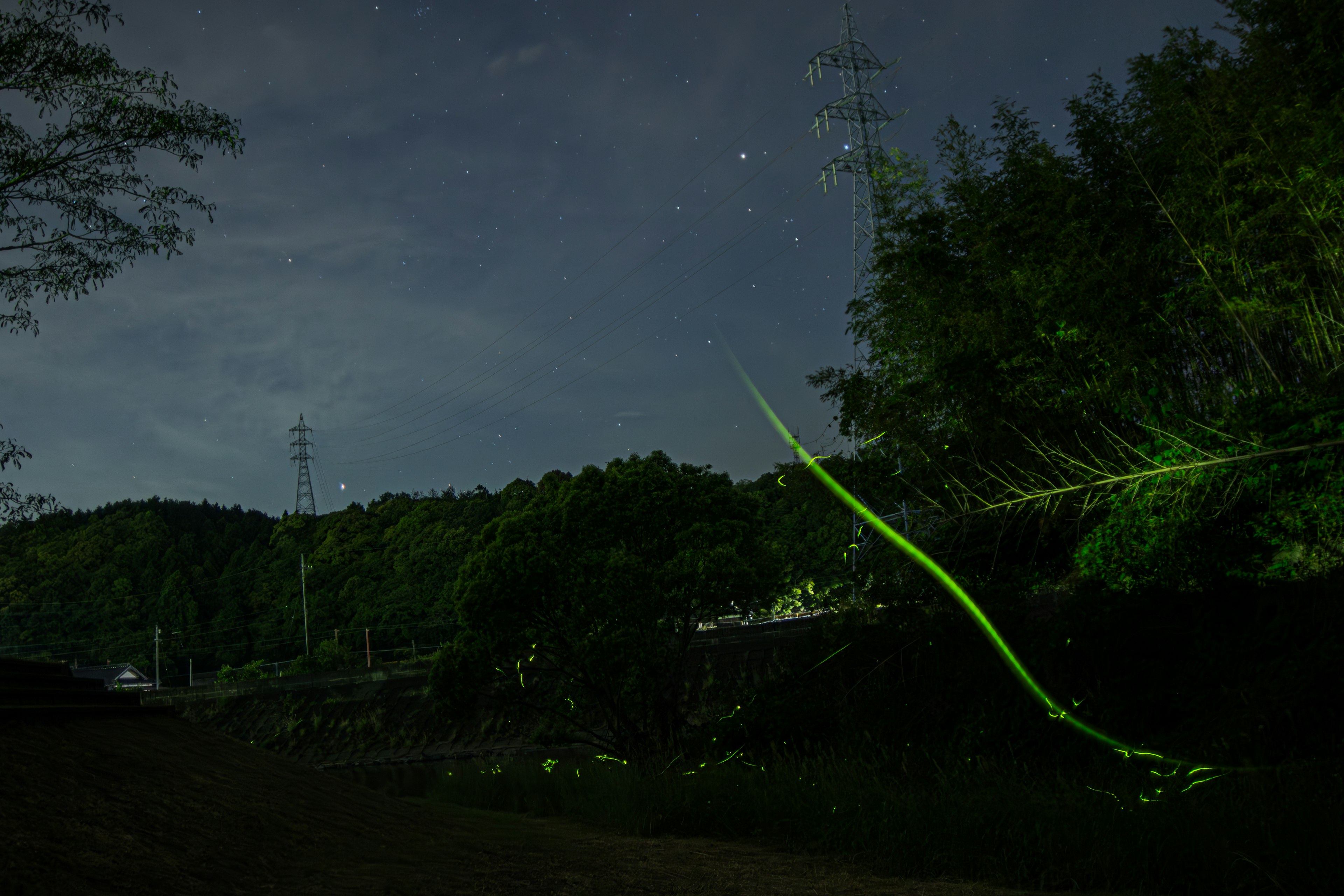 Rayas de luz verde contra un cielo nocturno oscuro y silueta de montaña