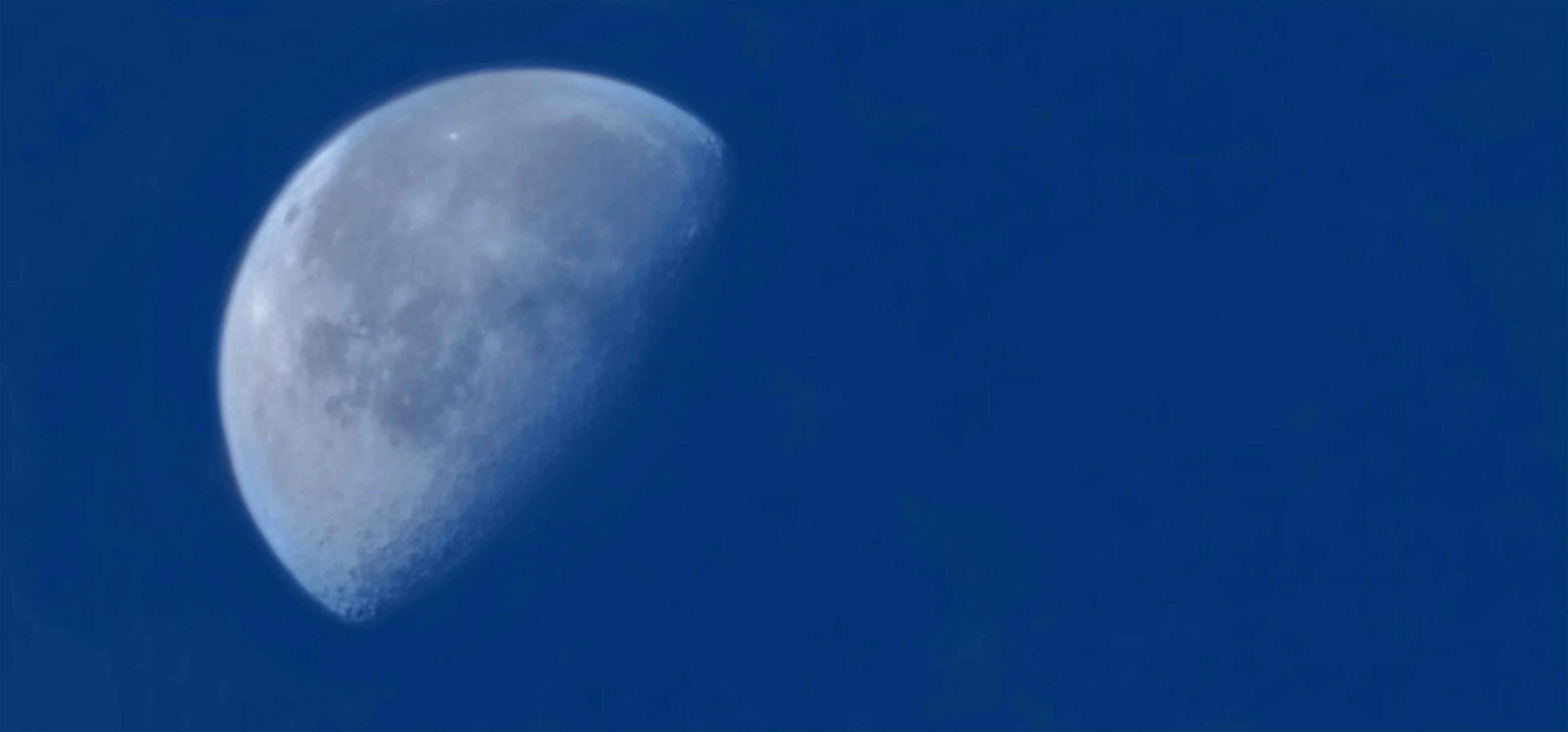 Image détaillée d'une lune croissante dans un ciel bleu