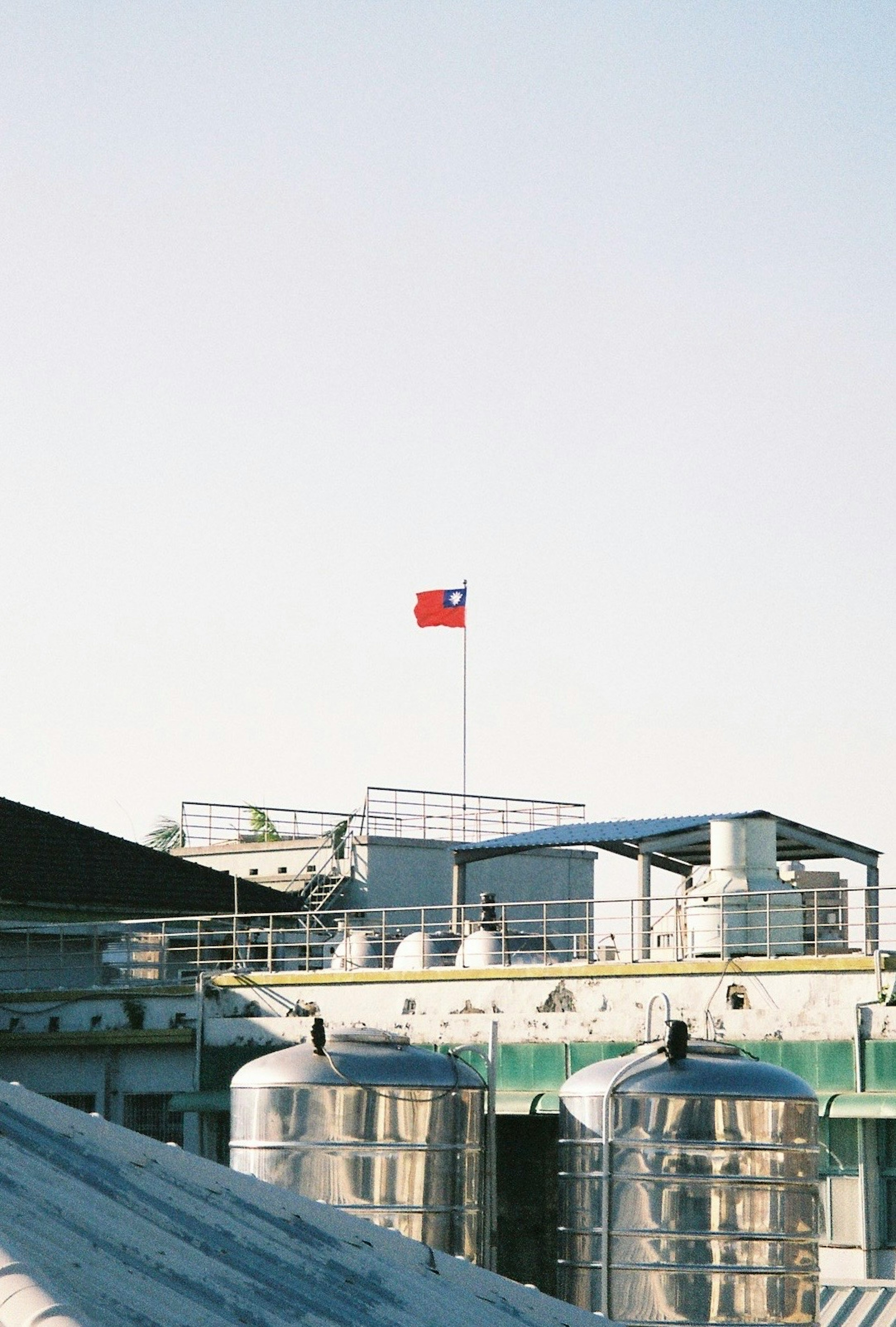 Taiwanese flag flying above rooftops and metal tanks under a clear blue sky