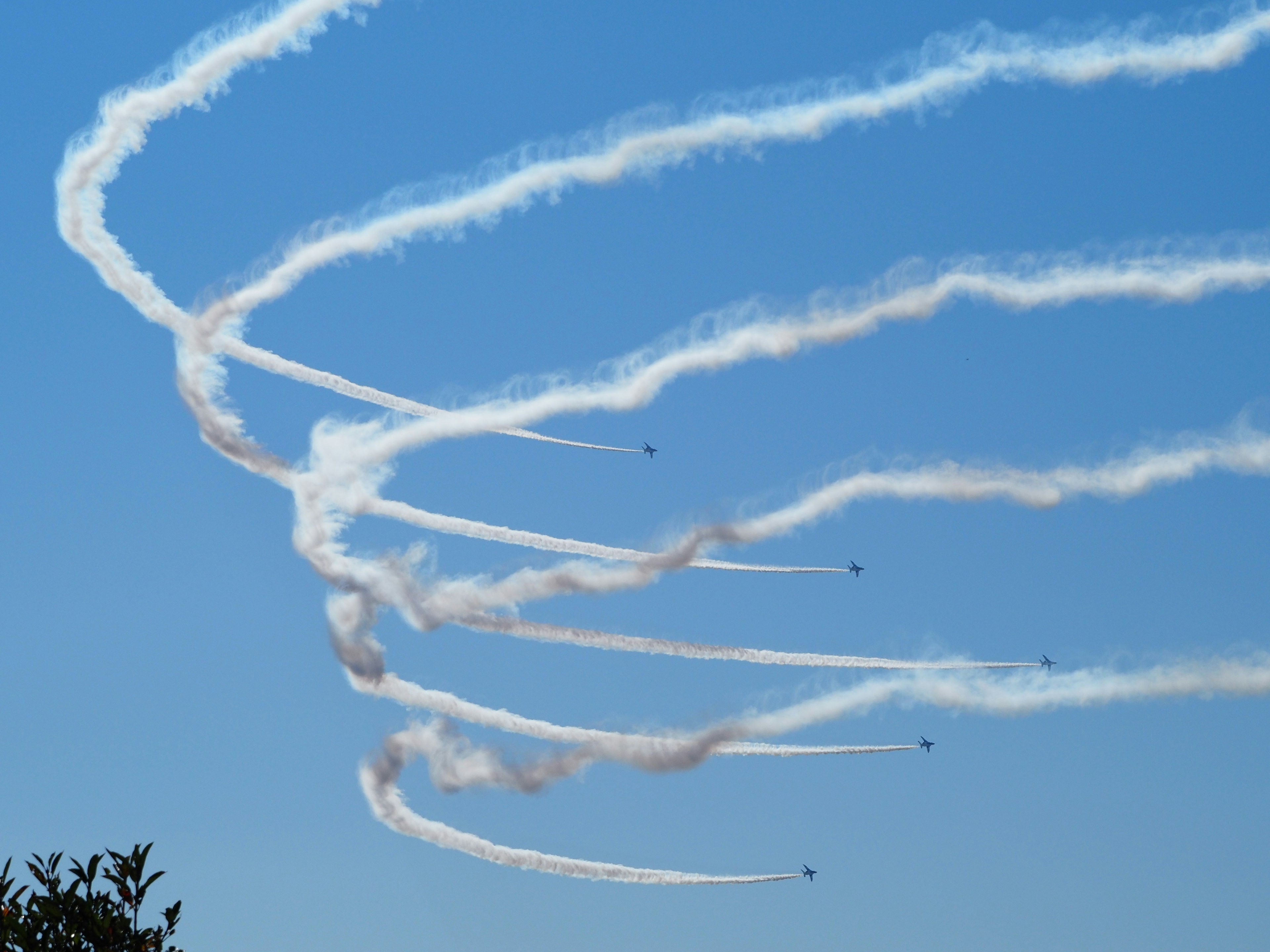 Estelas de humo blanco en un cielo azul de maniobras aéreas