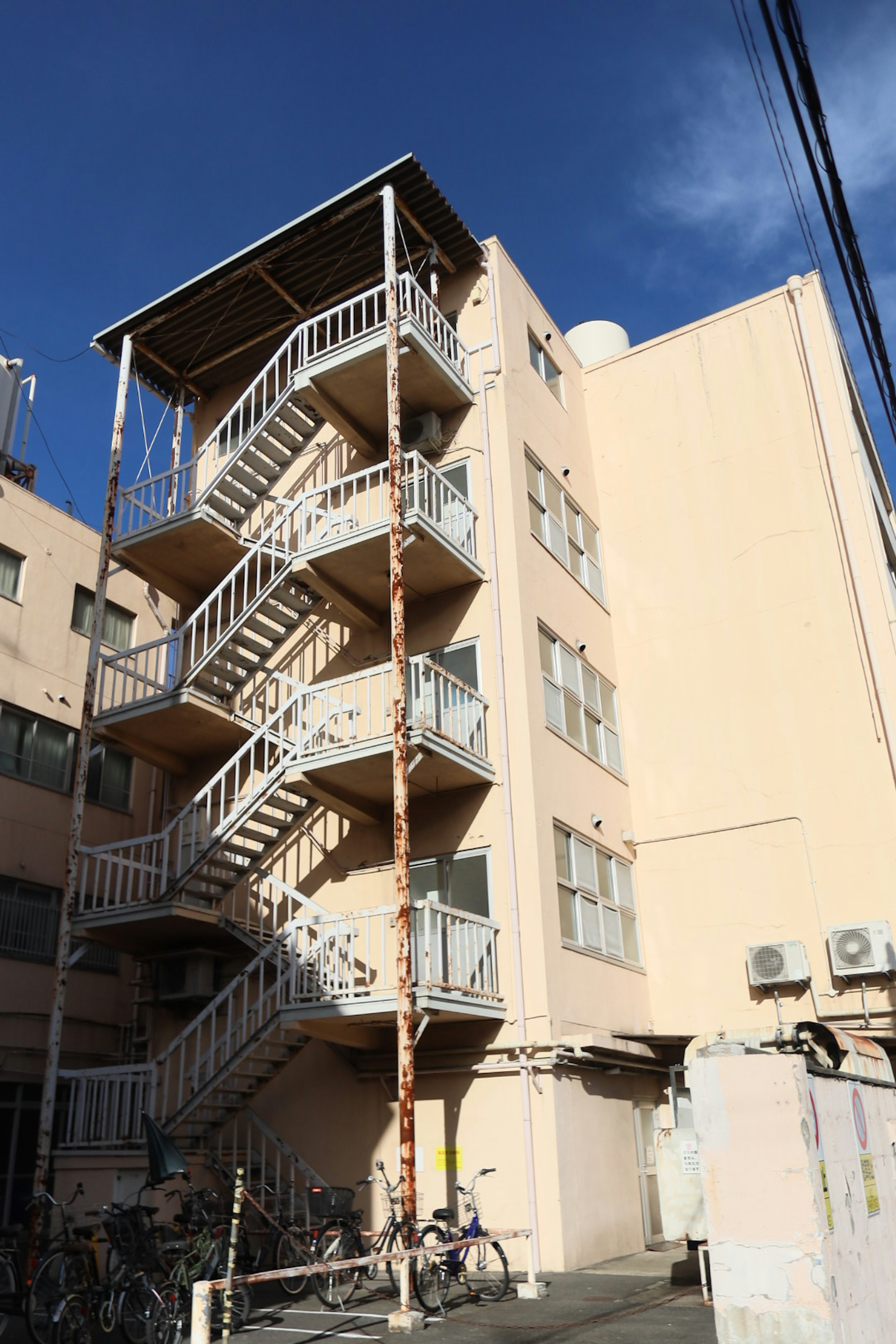 Exterior de un edificio rosa con una escalera de metal blanco